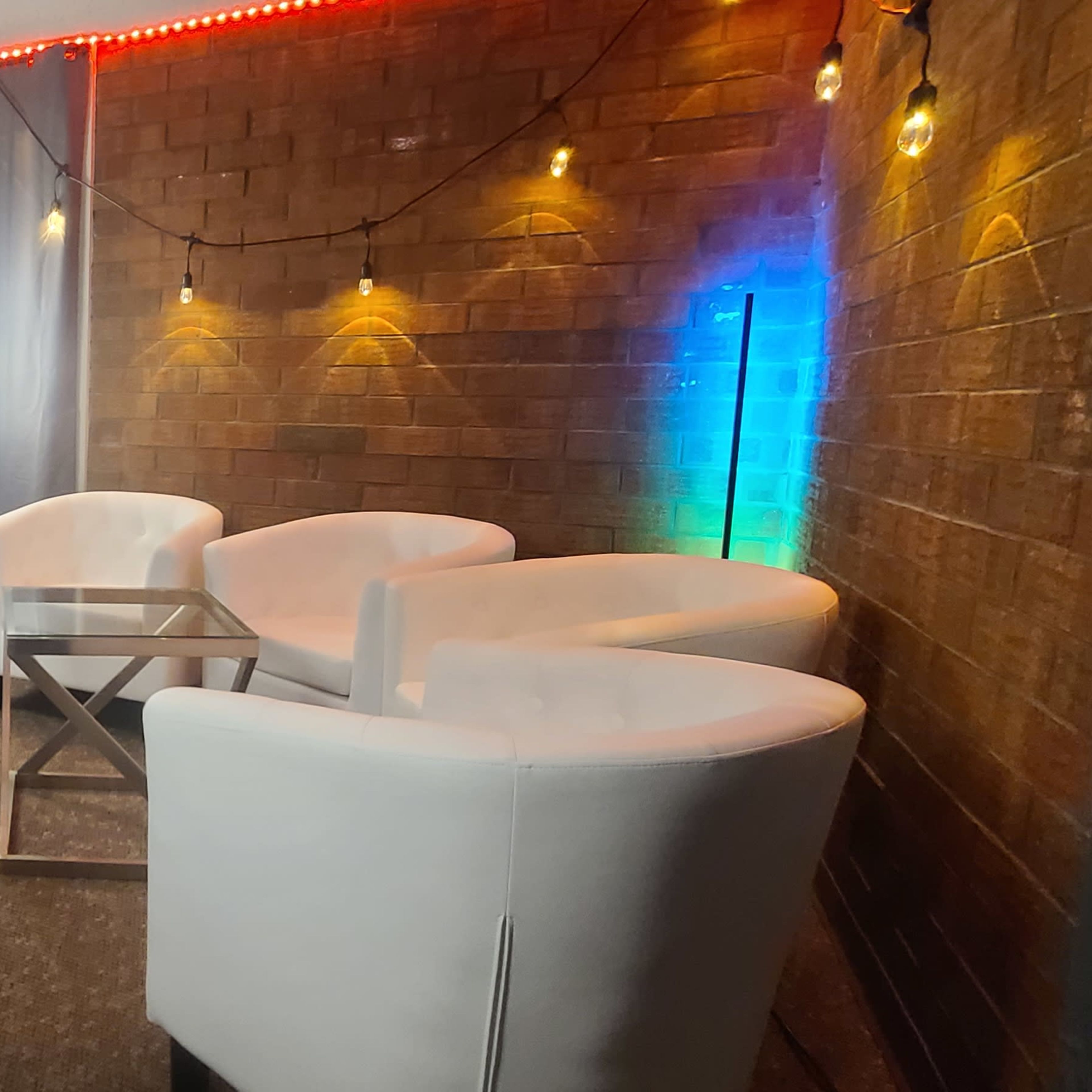 A modern studio setup features a table and chairs surrounded by decorative lights and acoustic panels.