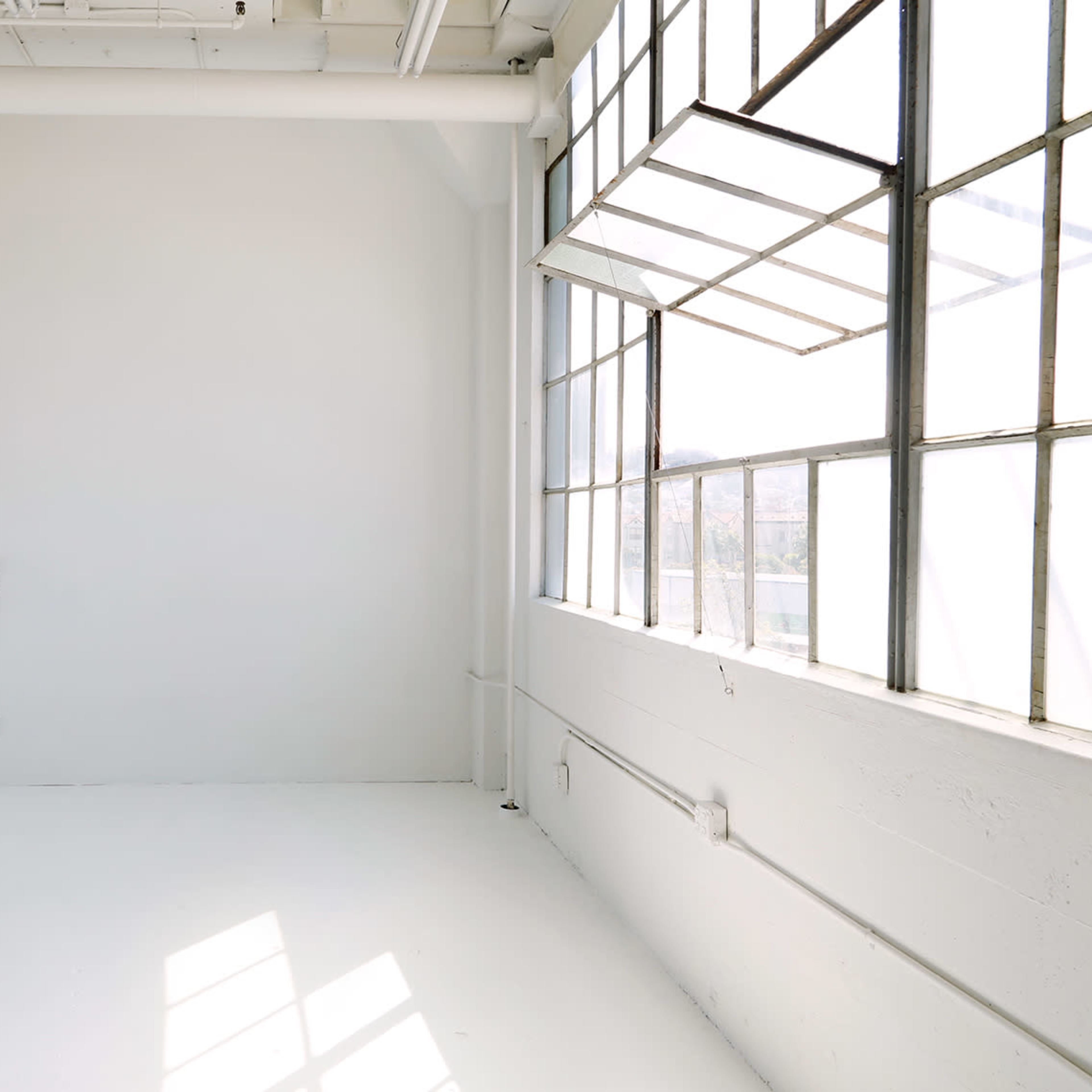A bright, sparsely furnished room with large windows and white walls.