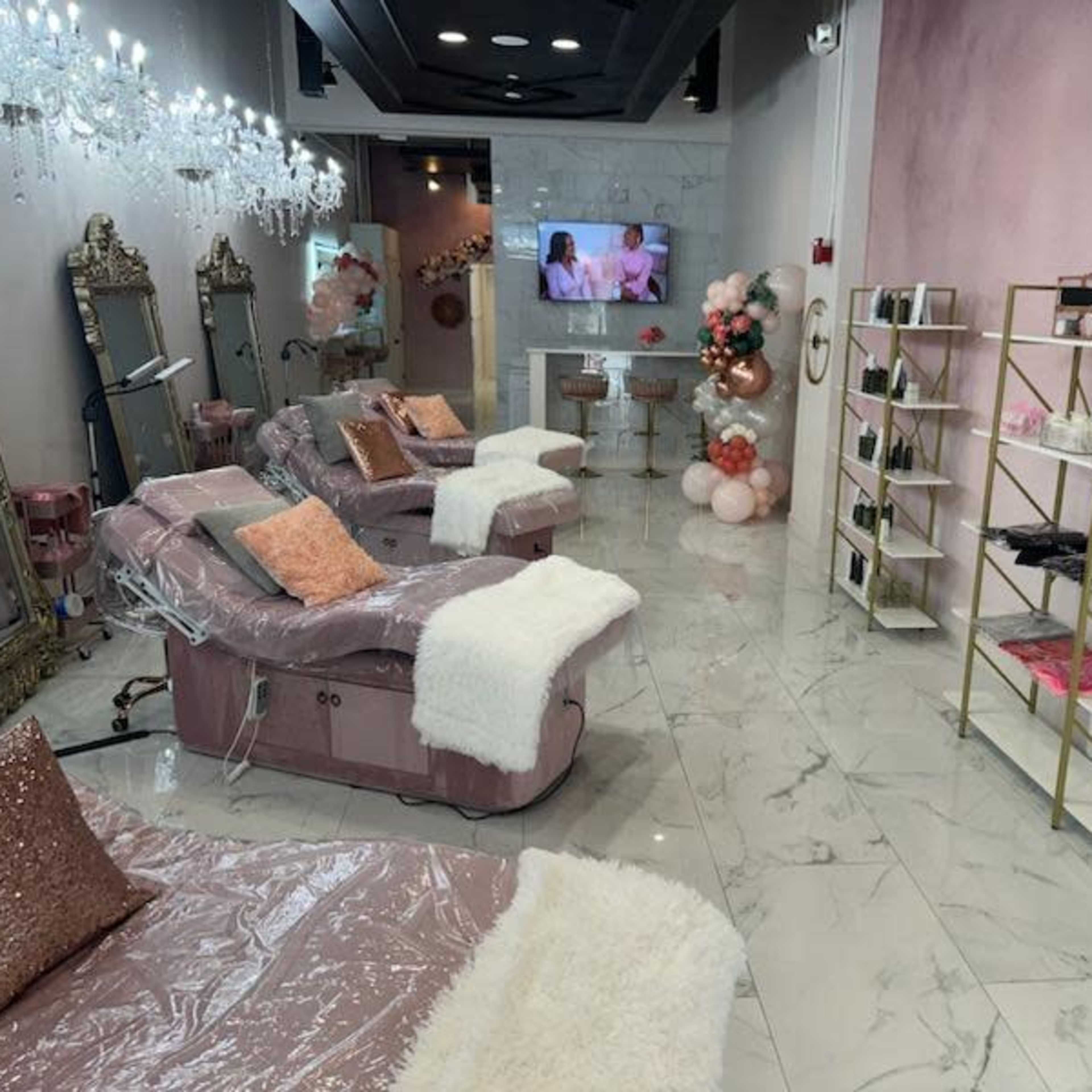 A beautification salon interior featuring plush seating, elegant mirrors, decorative lighting, and a display shelf with various beauty products.