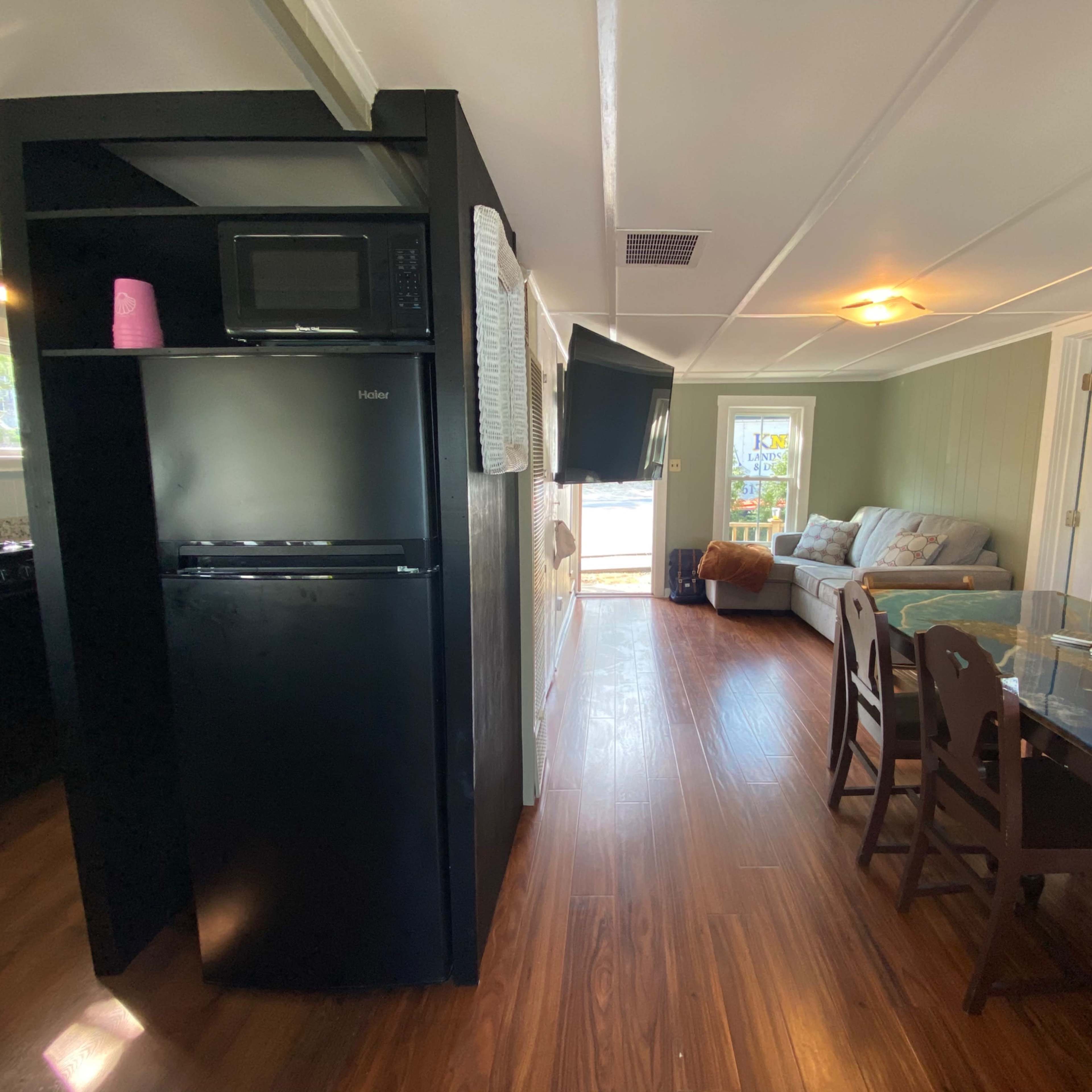A small living space with a kitchenette, a dining area, and a seating area that features a sofa and a television.