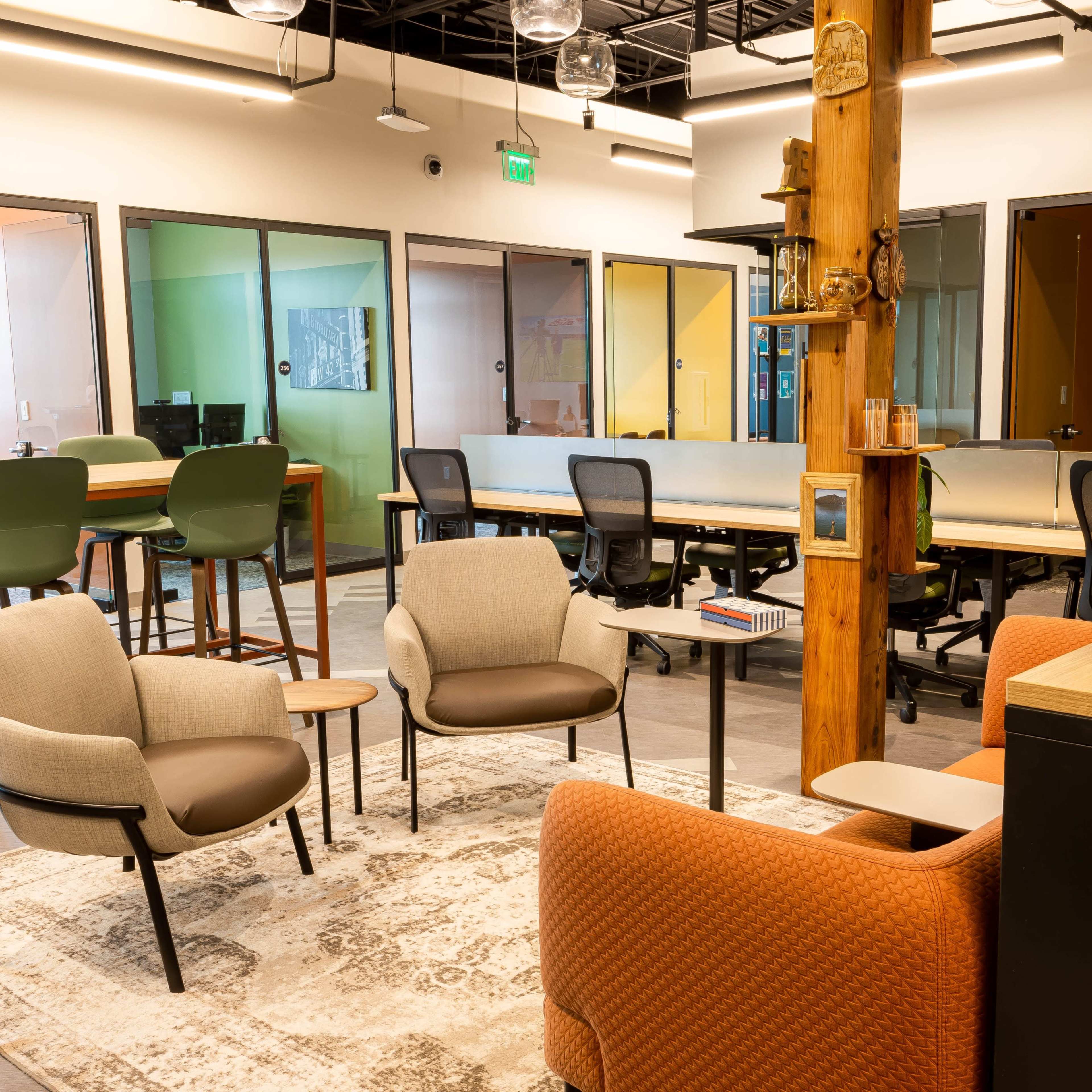 A modern office space with seating arrangements, workstations, and colorful glass partitions.