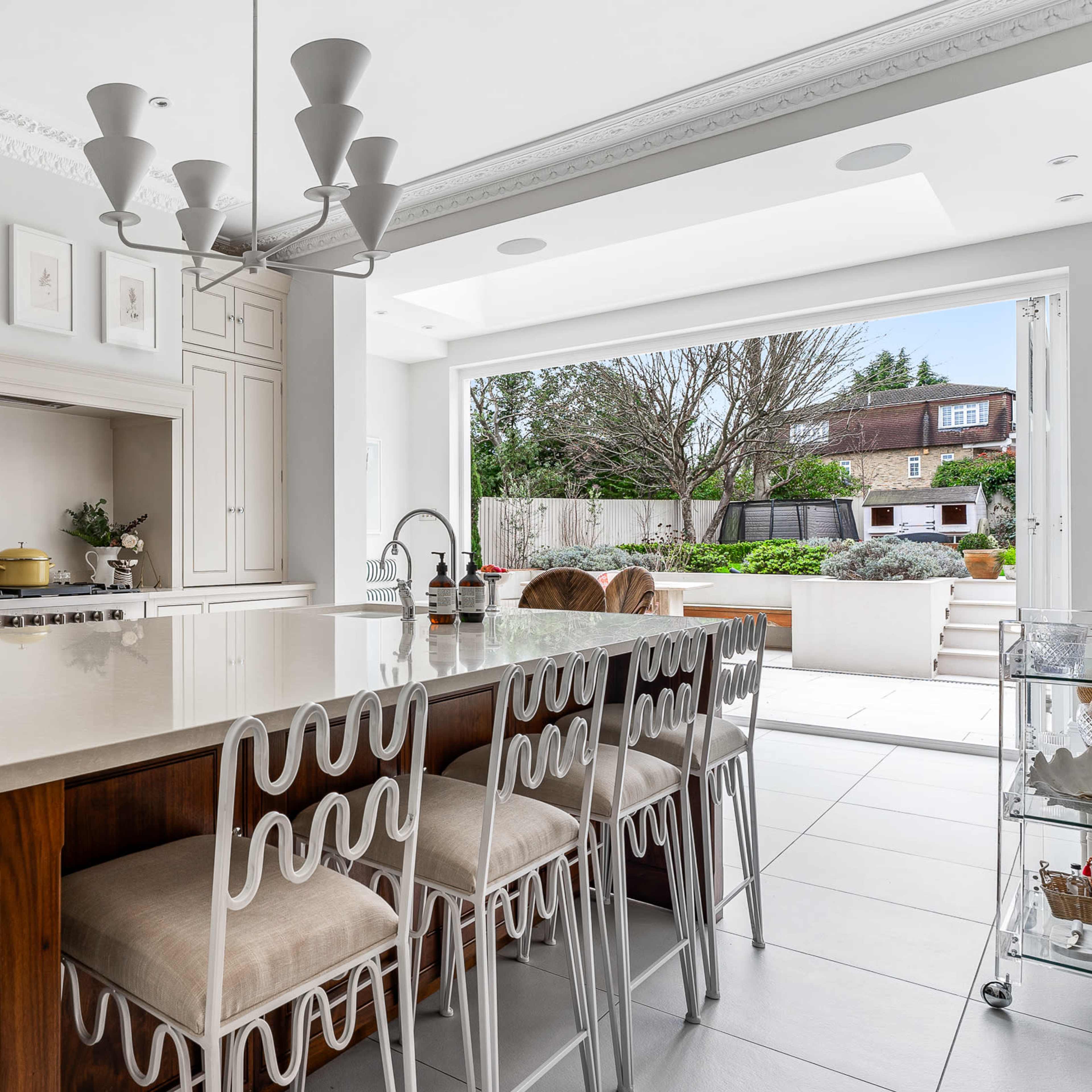 A modern kitchen with a large island featuring seating, stylish cabinetry, and an open layout leading to an outdoor space.