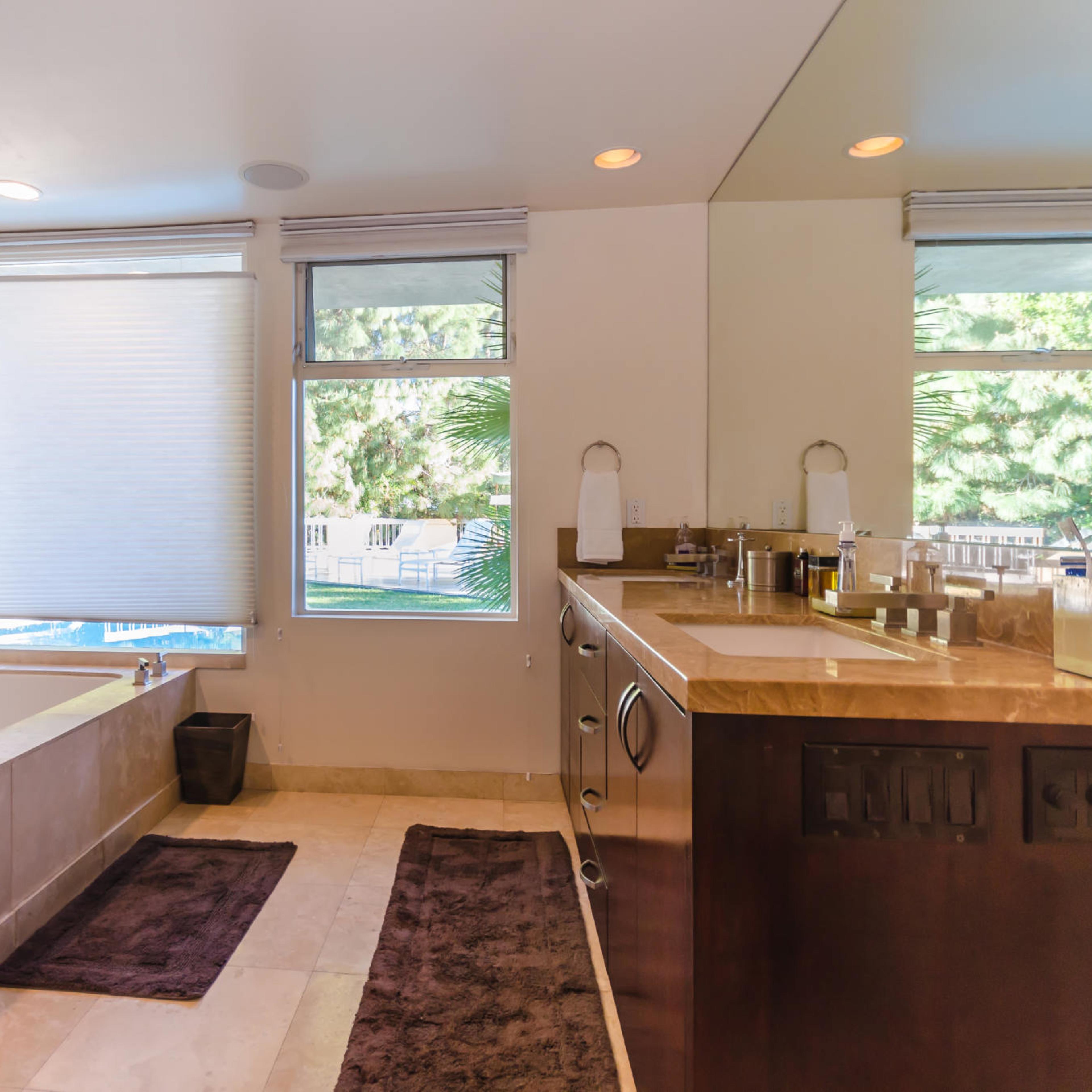 A modern bathroom featuring a freestanding bathtub, a double vanity, and a large window with natural light.