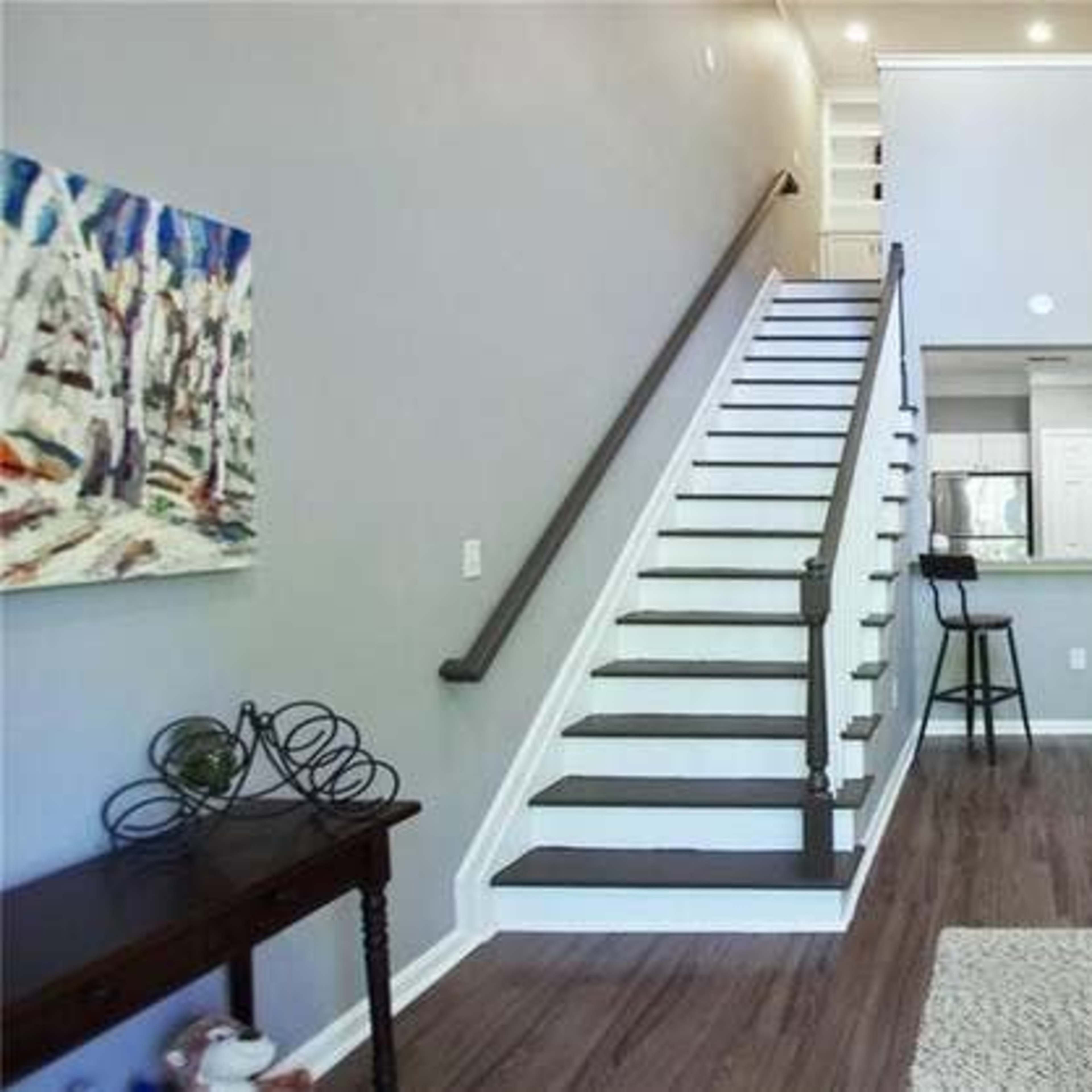 A modern living area with a staircase leading to an upper level, a sofa, and a small dining area in the background.