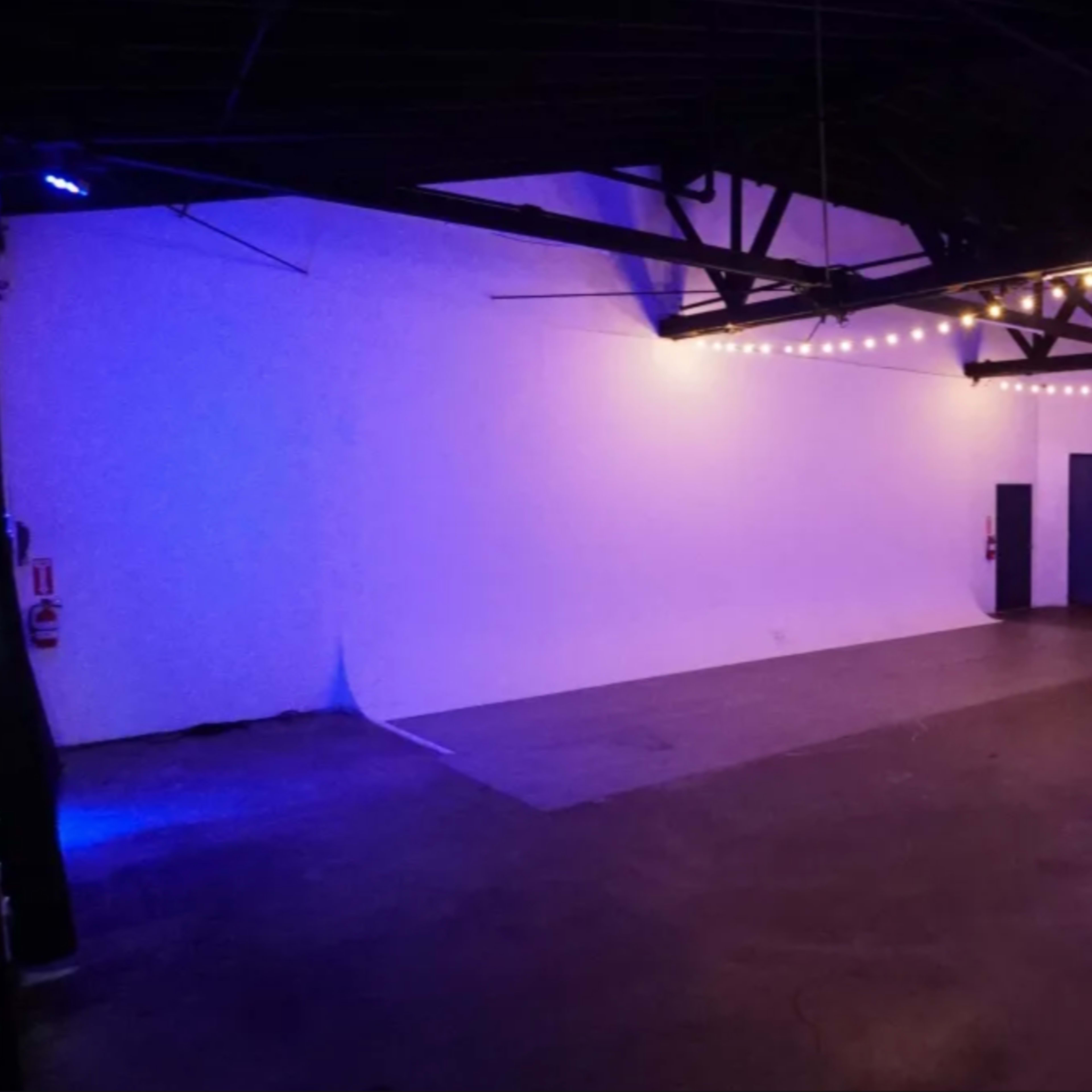 A spacious, empty venue with a polished concrete floor and purple accent lighting.