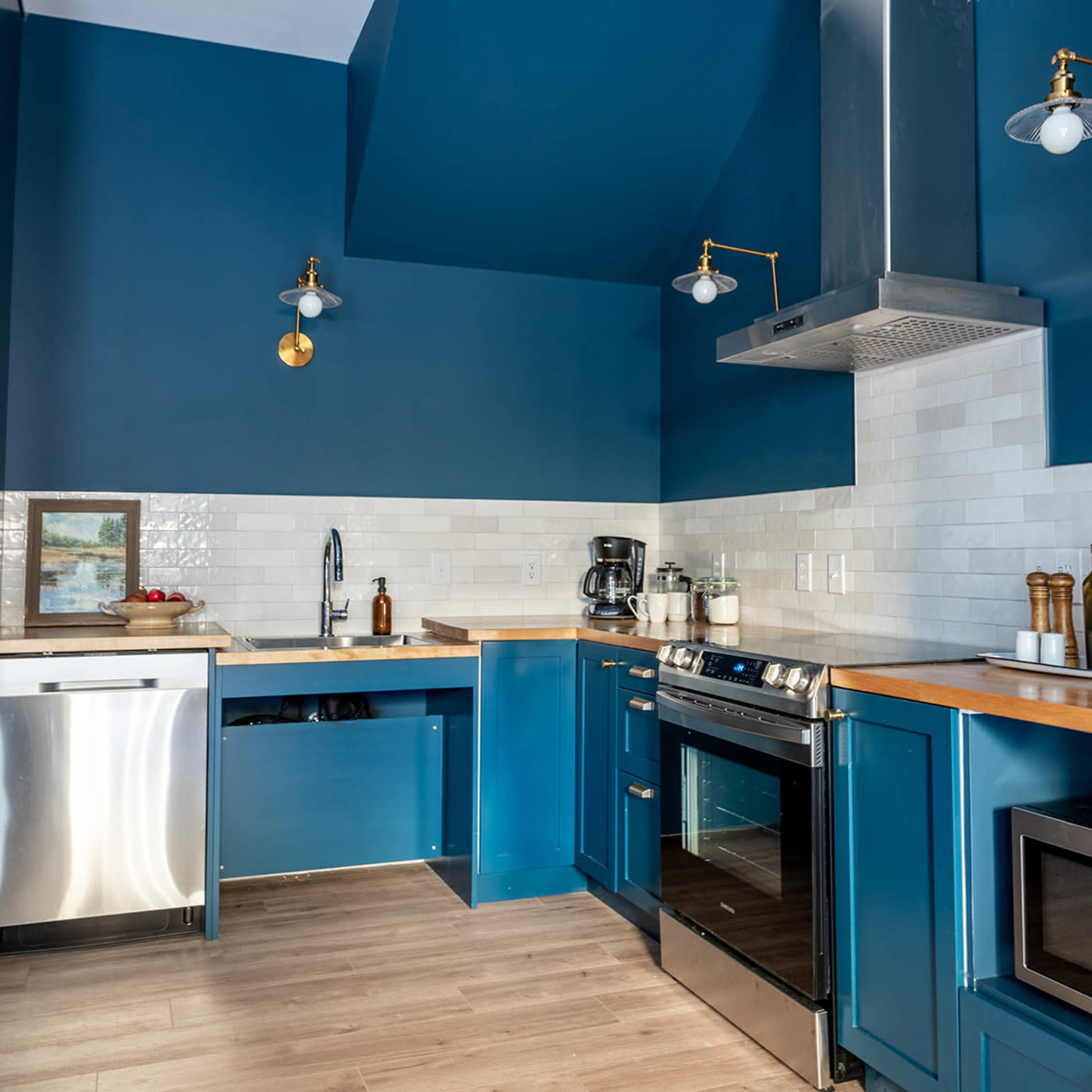 The kitchen features blue cabinetry, stainless steel appliances, and a wooden countertop.