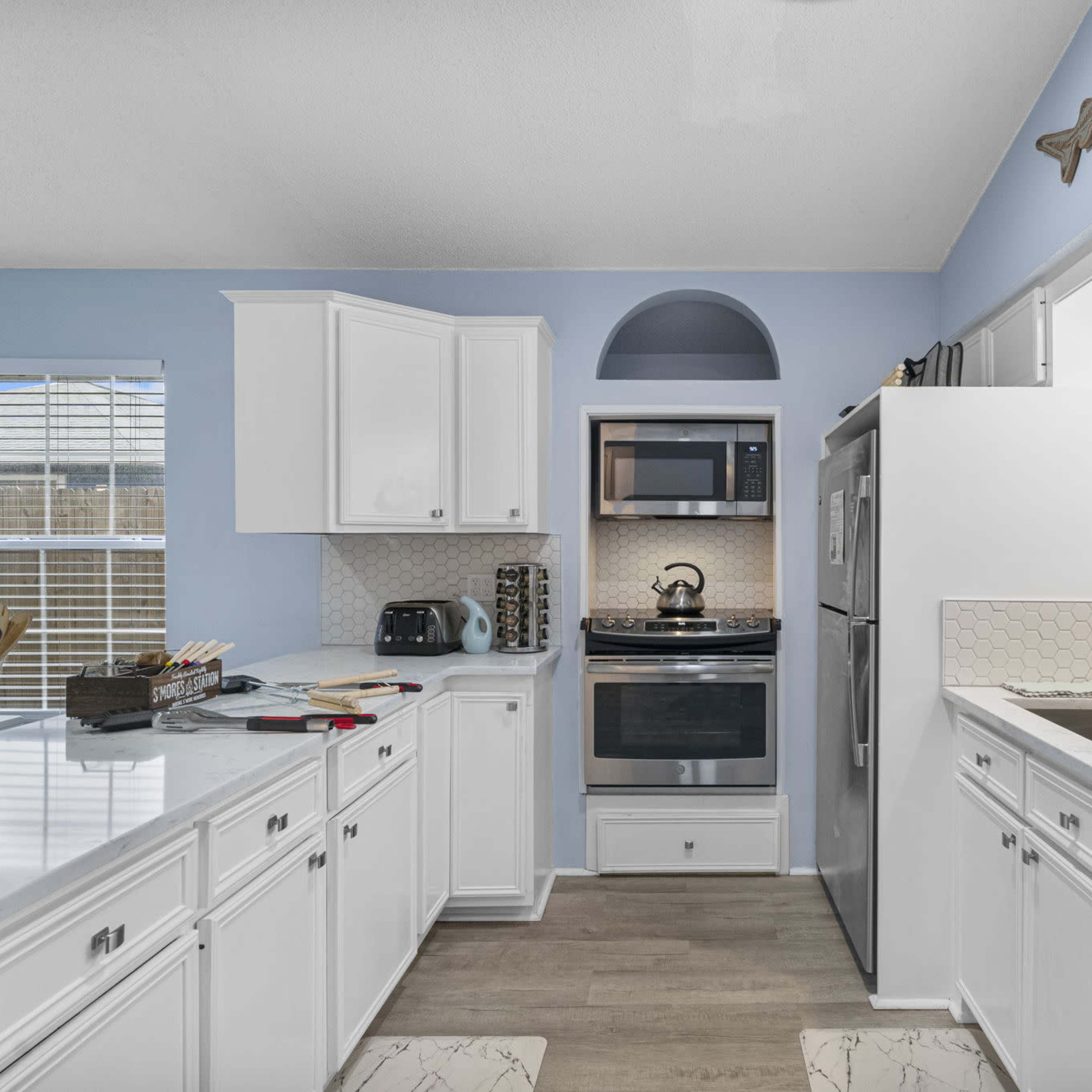 A bright kitchen featuring white cabinetry, stainless steel appliances, and a coffee bar on the counter.