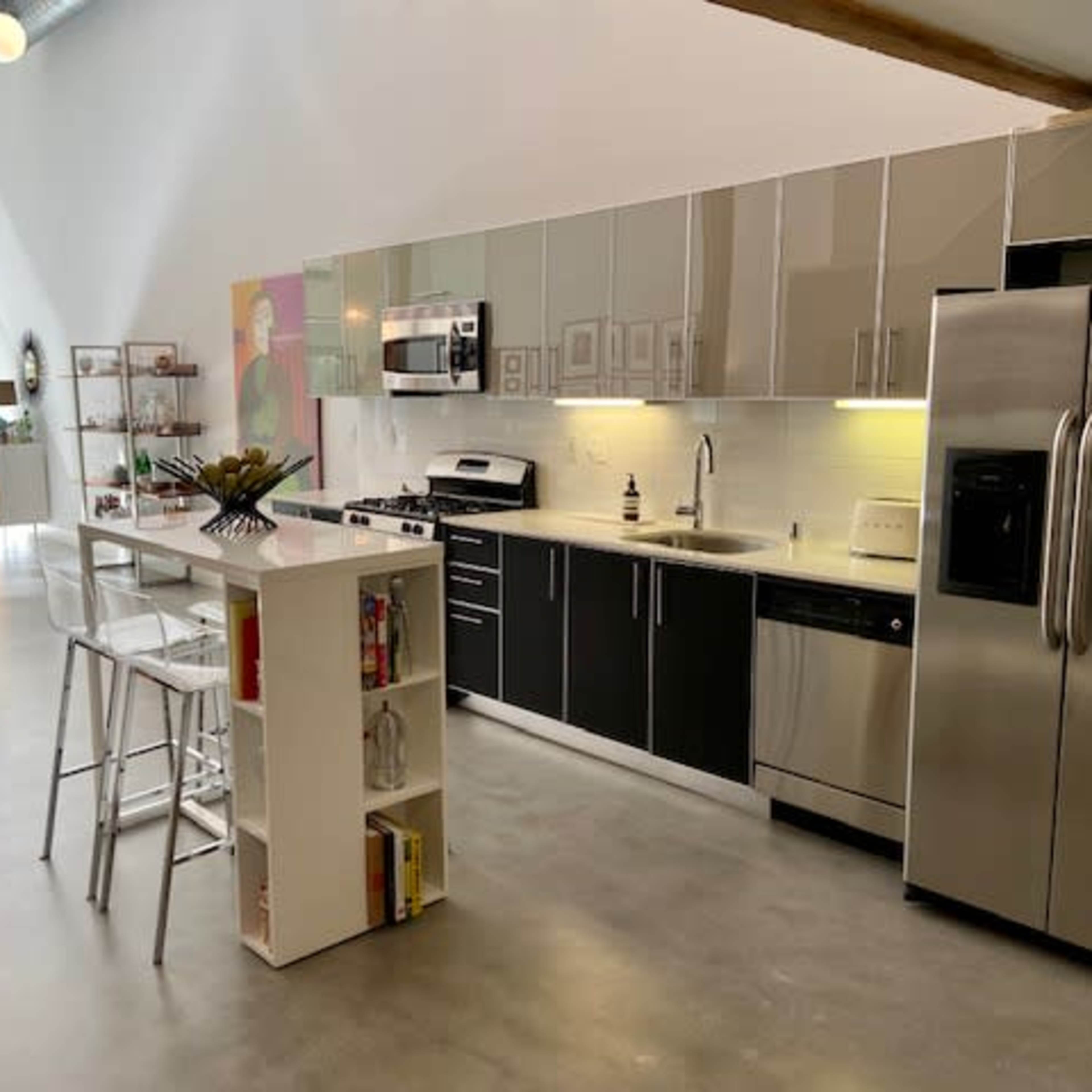 A modern kitchen with sleek cabinets, stainless steel appliances, and a dining area featuring a round table and white chairs.