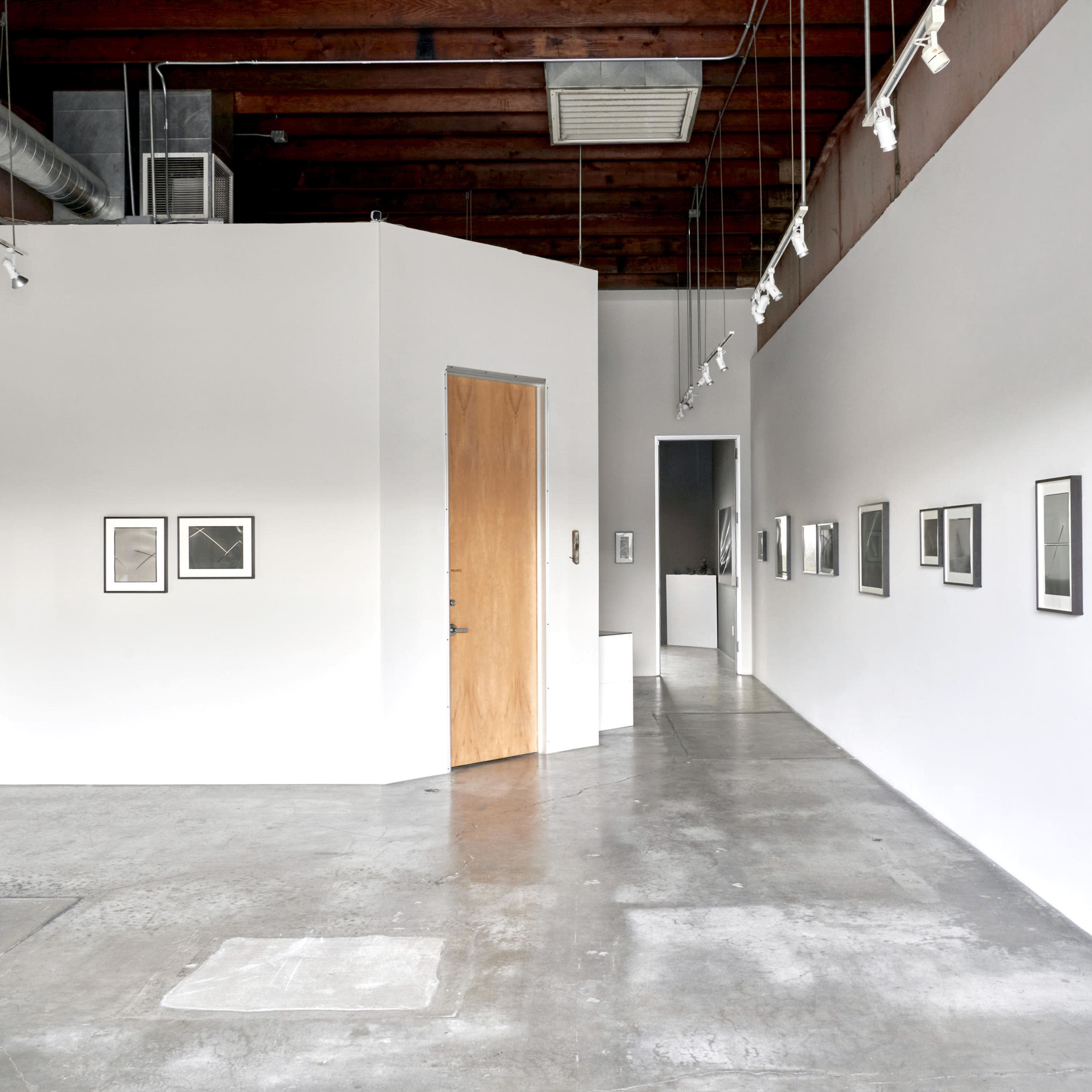 A modern art gallery featuring framed black and white photographs on white walls and a concrete floor.