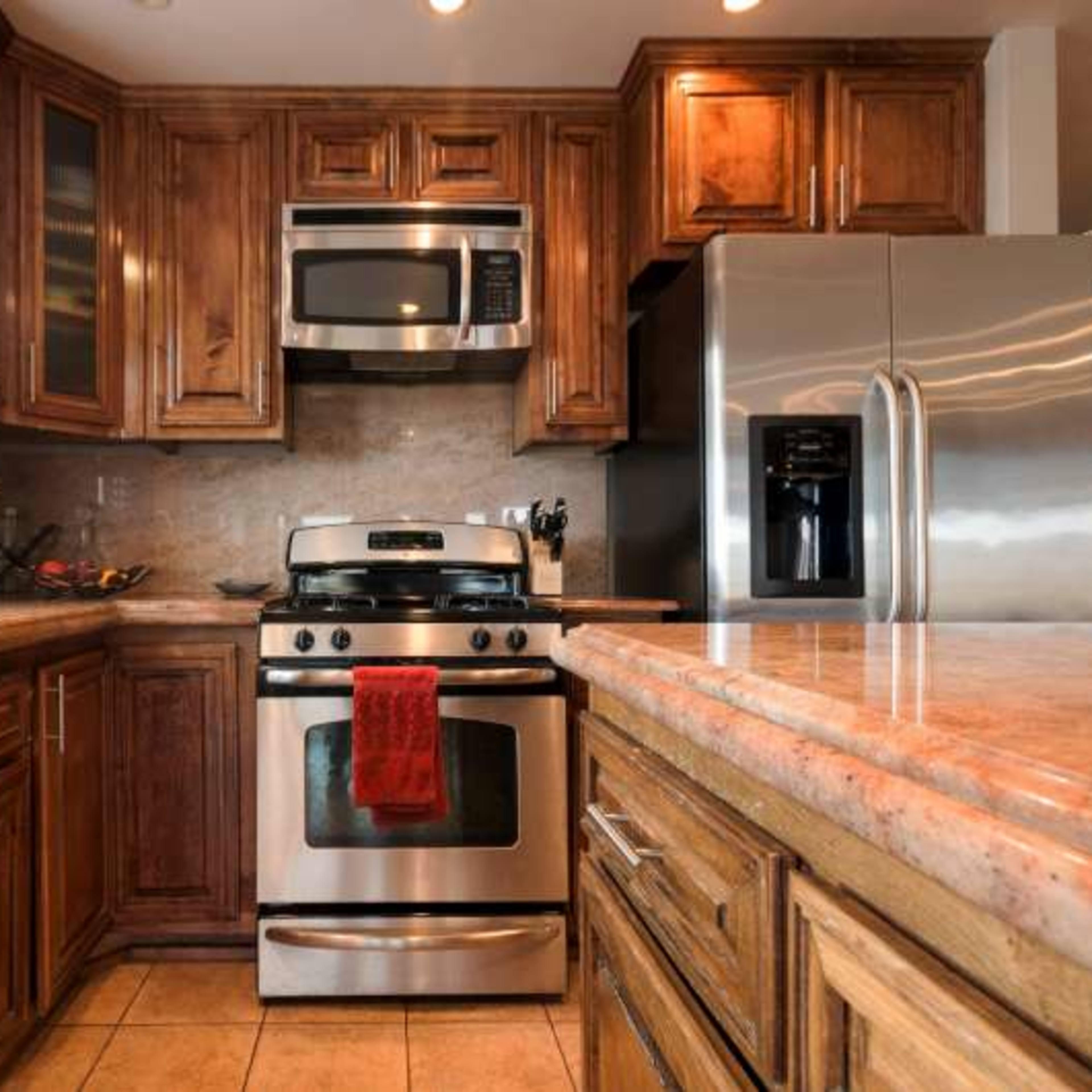 A modern kitchen with wooden cabinets, stainless steel appliances, and a granite countertop.