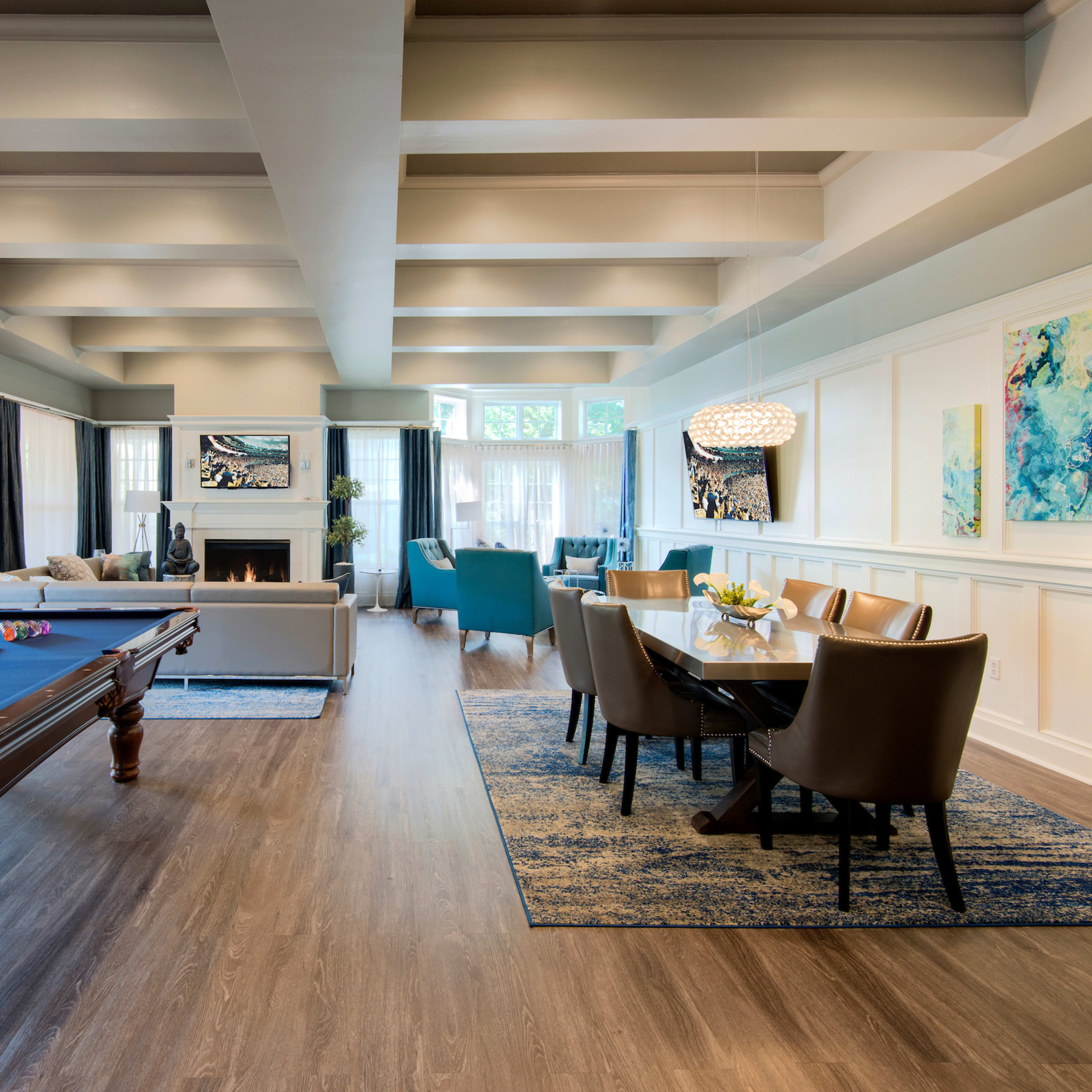 A spacious living area featuring a pool table, a dining table, and large windows that allow natural light to fill the room.