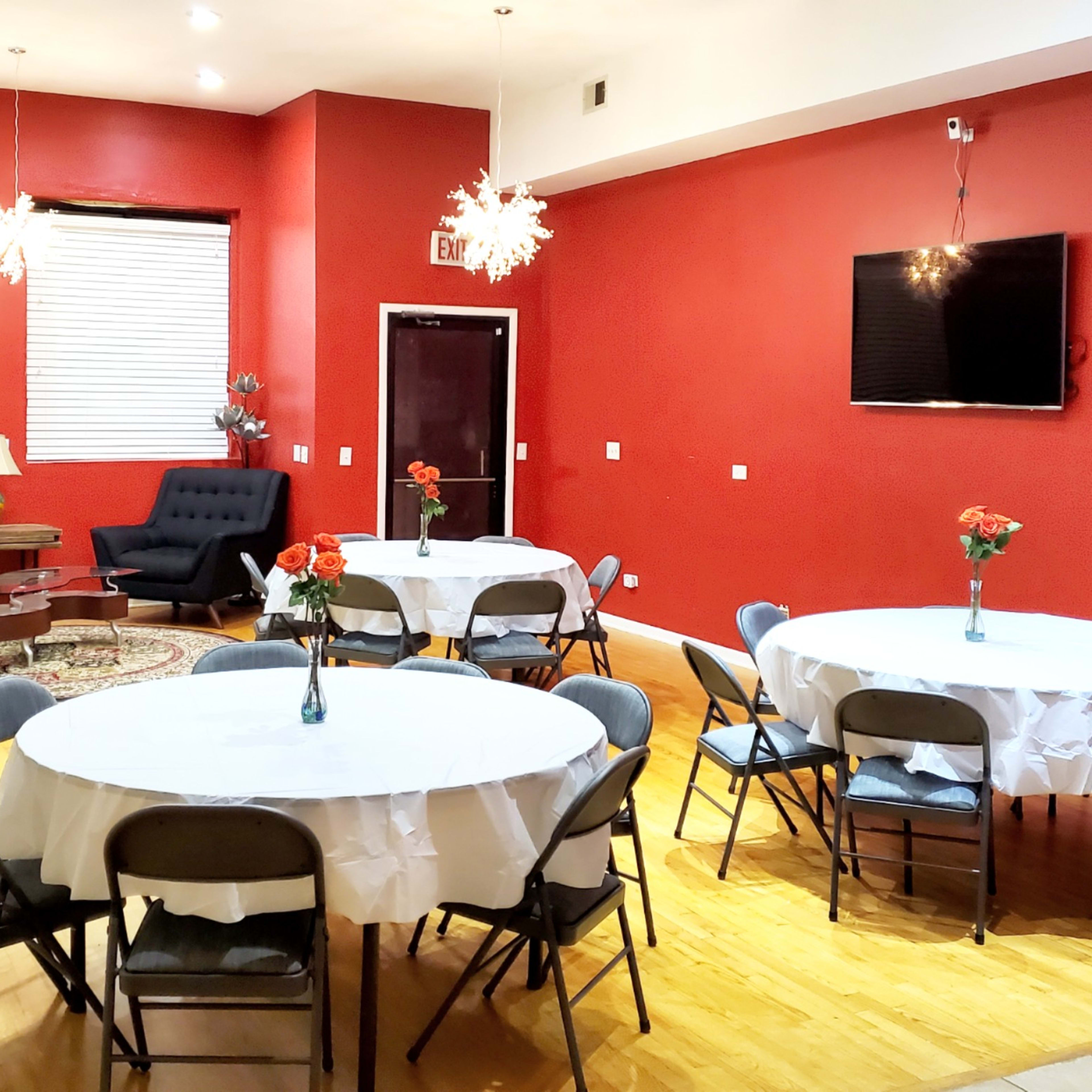 A small, elegantly arranged room with round tables set for dining, surrounded by comfortable seating and accented by modern light fixtures.