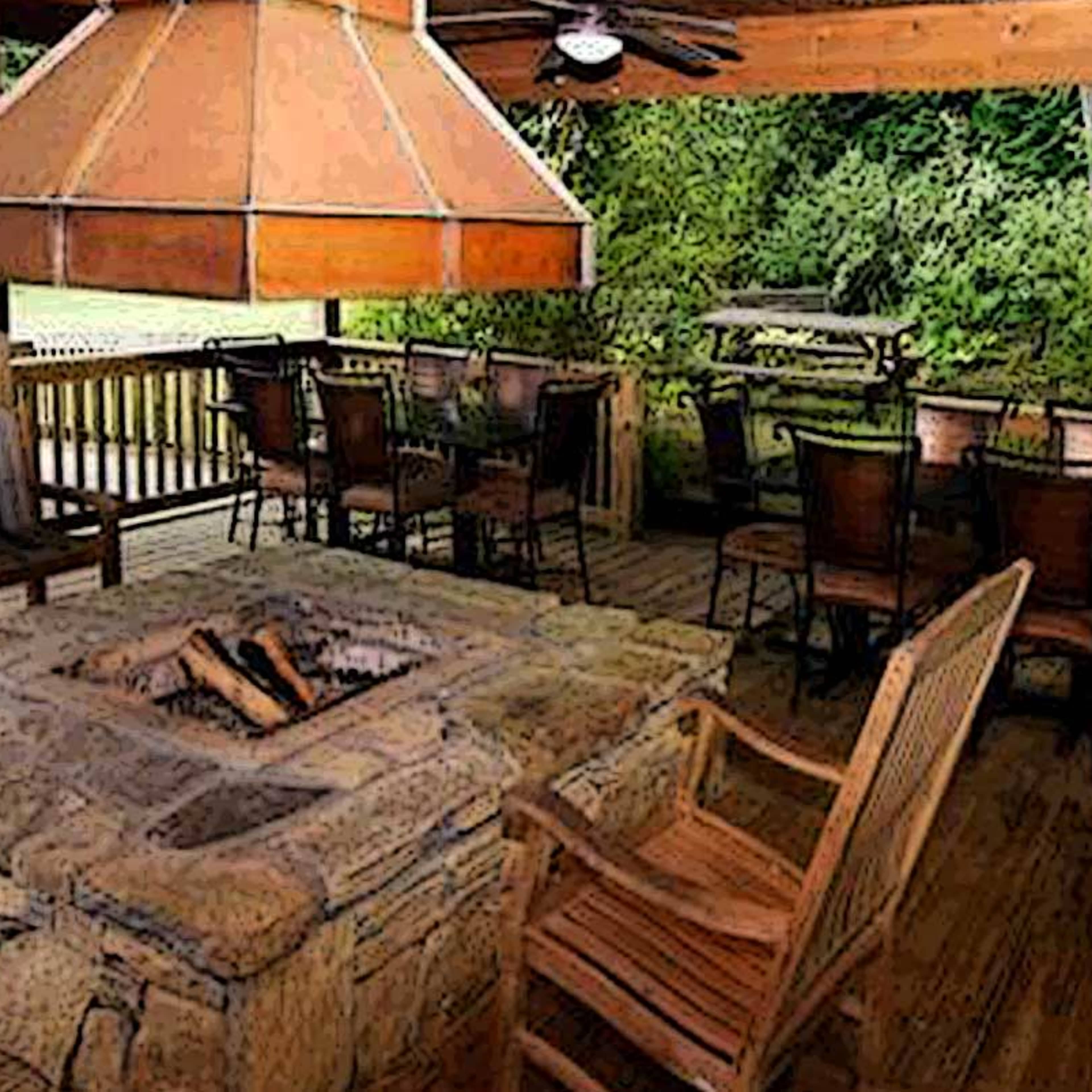 A wooden deck area with a stone fire pit at the center, surrounded by seating and a covered structure overhead.