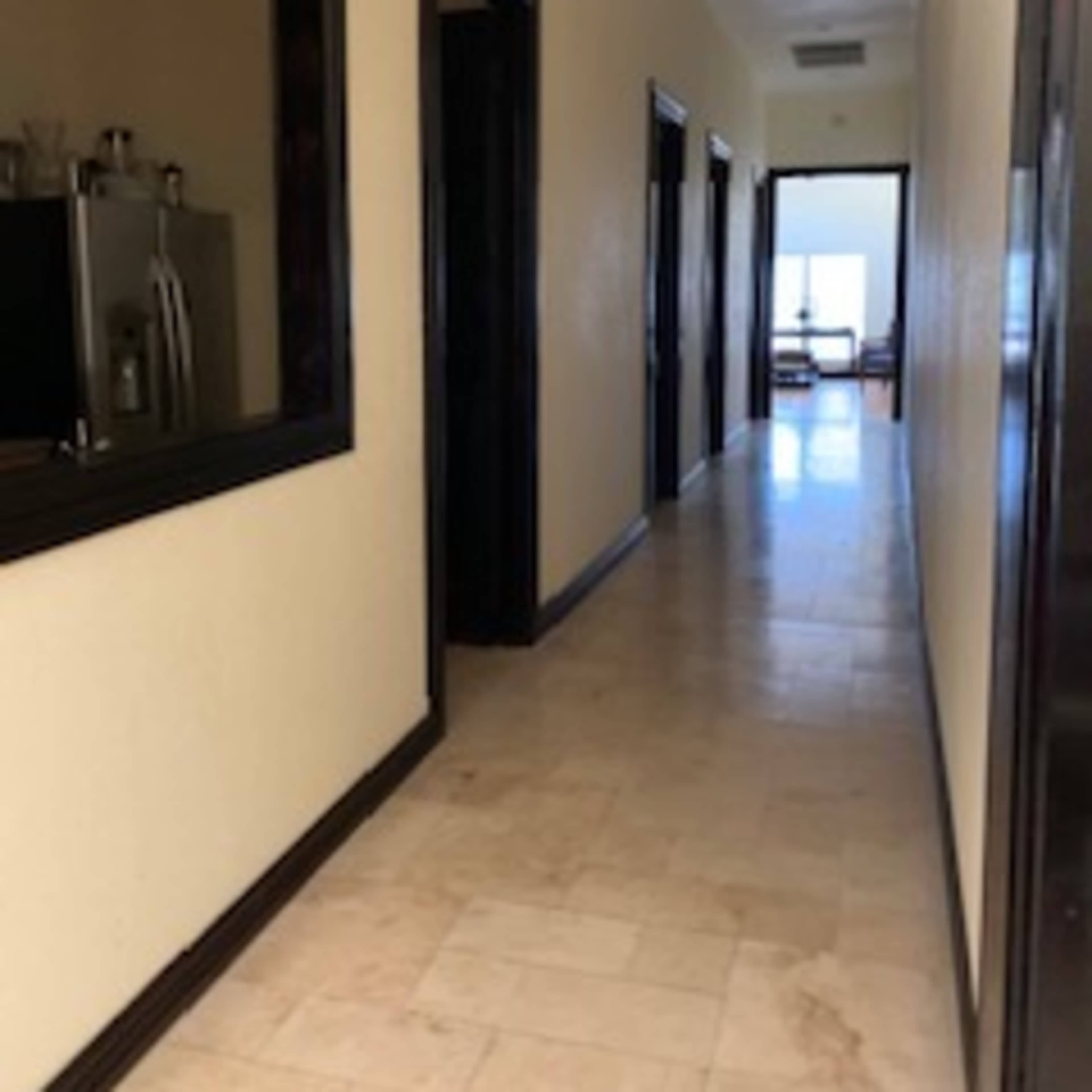 A long hallway with doorways on either side and a view of a room at the end.