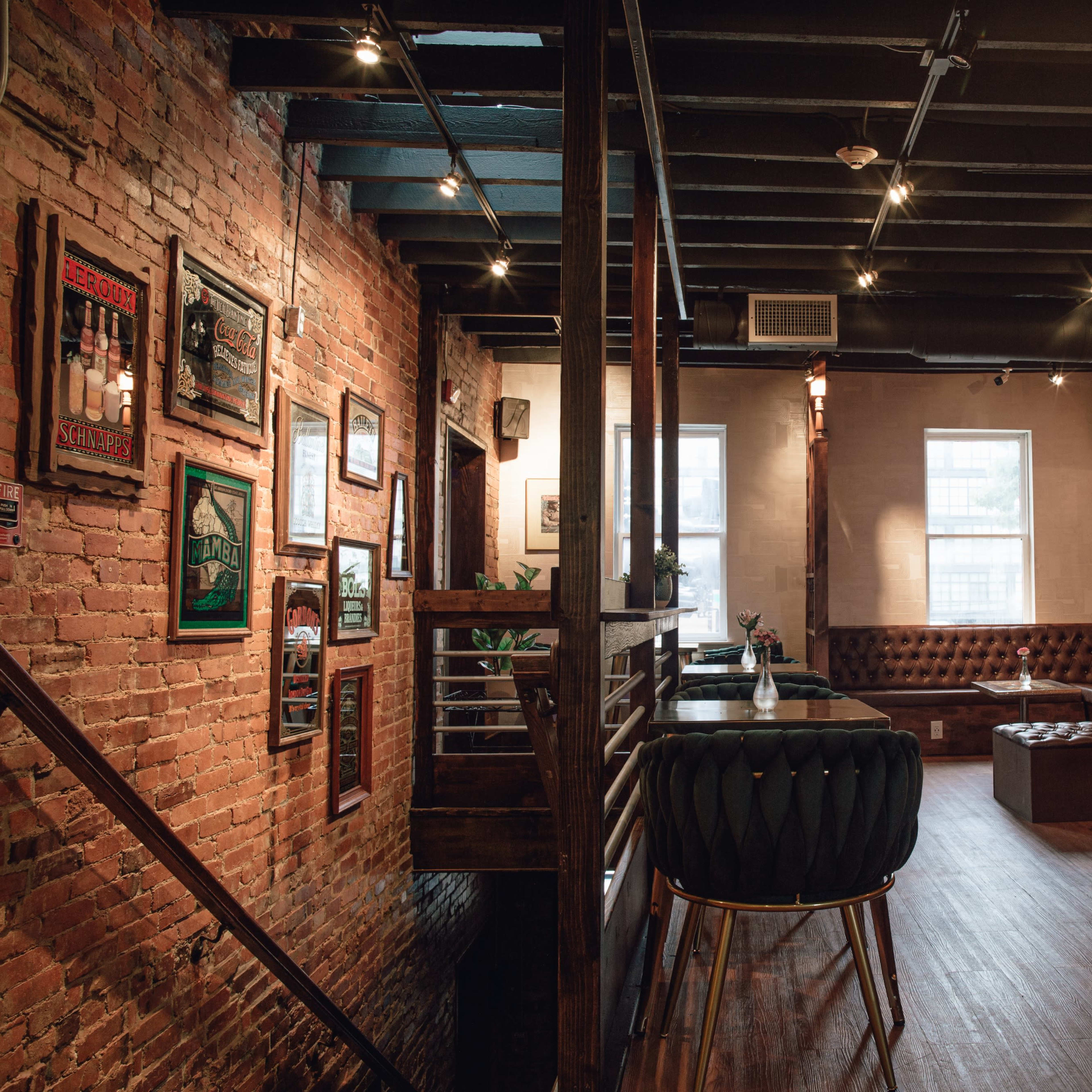 The interior of a restaurant features exposed brick walls, wooden beams, and a mix of leather seating and modern decor.