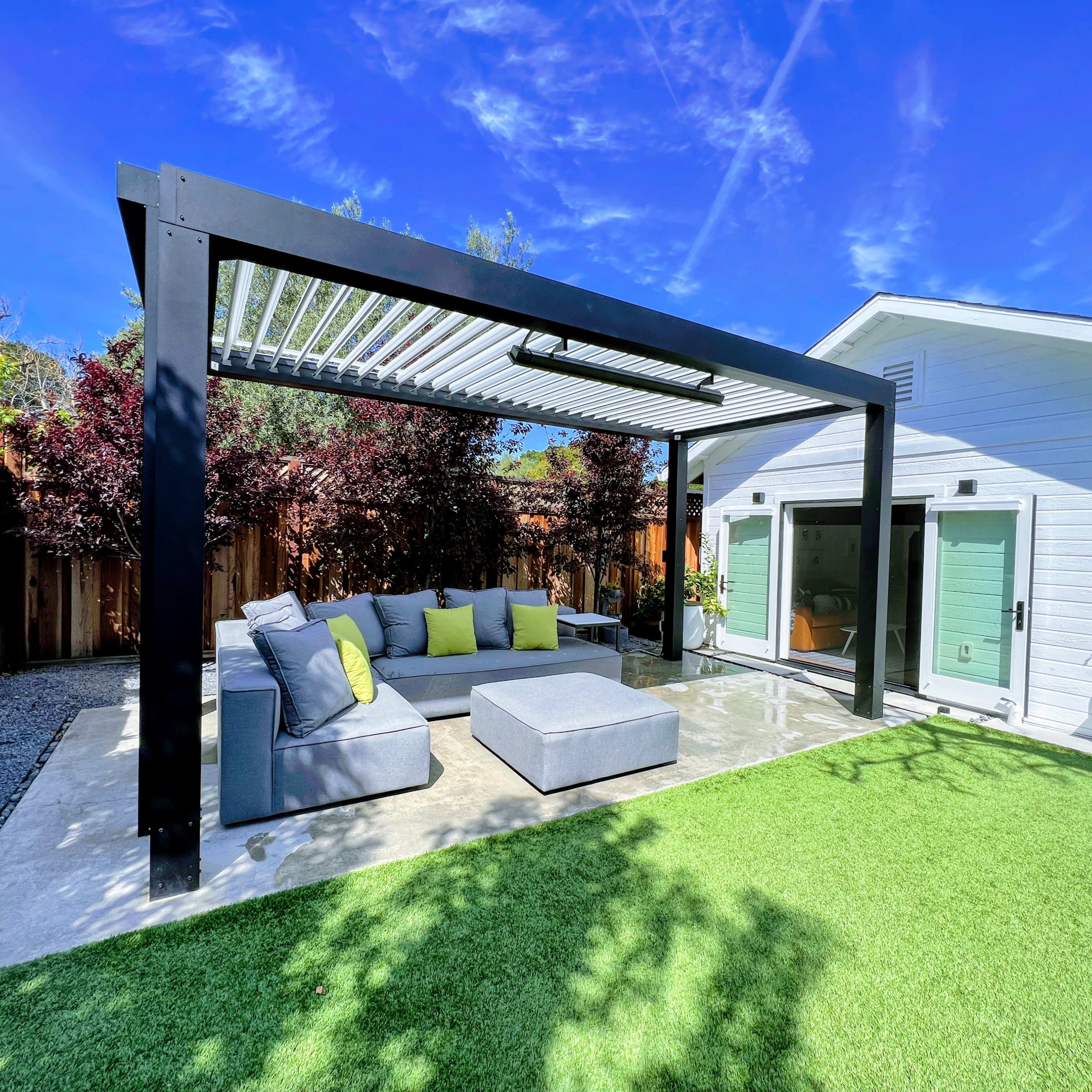 A modern outdoor lounging area with a pergola, featuring a sectional sofa and coffee table on a grassy lawn, adjacent to a white house.