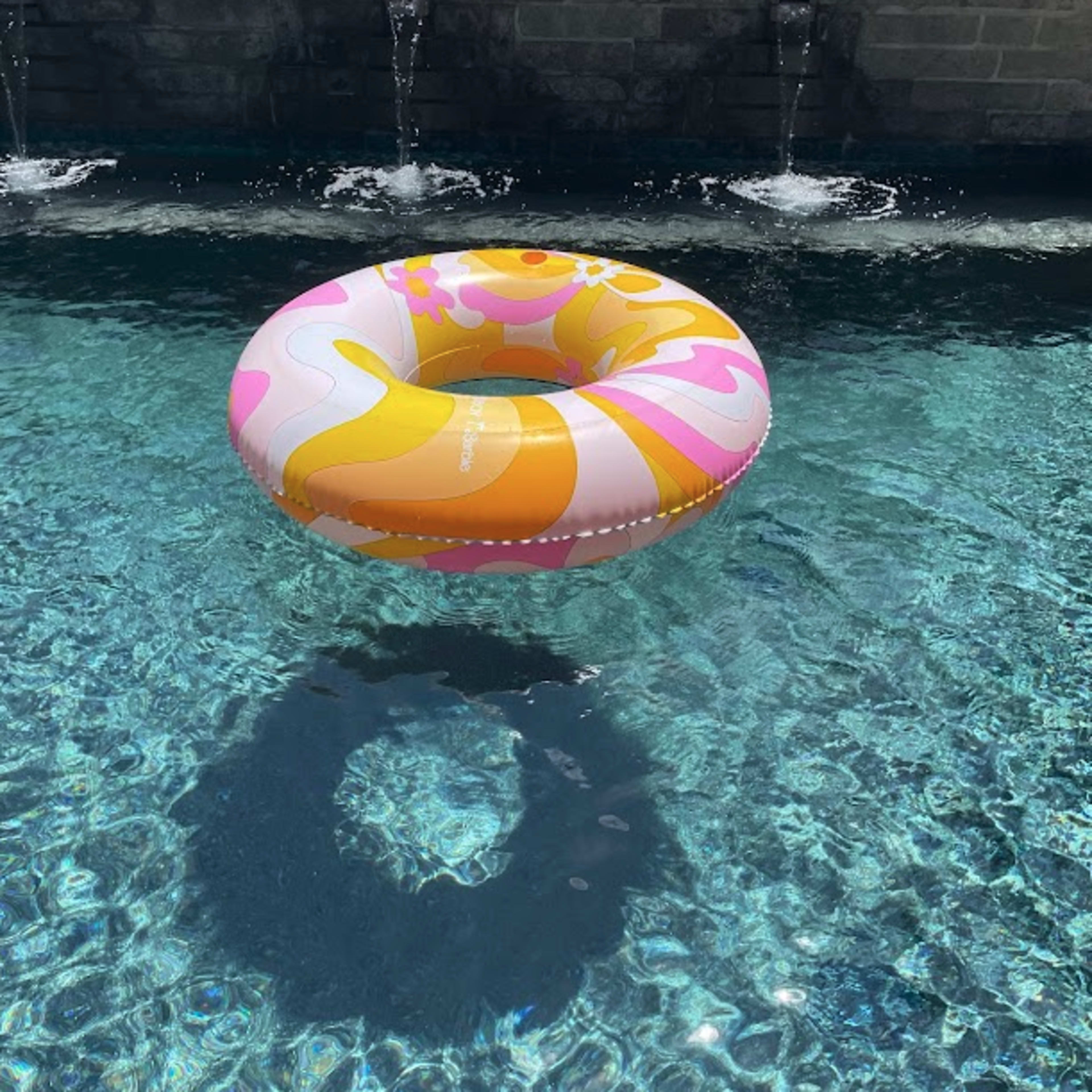 A colorful inflatable ring floats on the surface of a clear blue swimming pool.