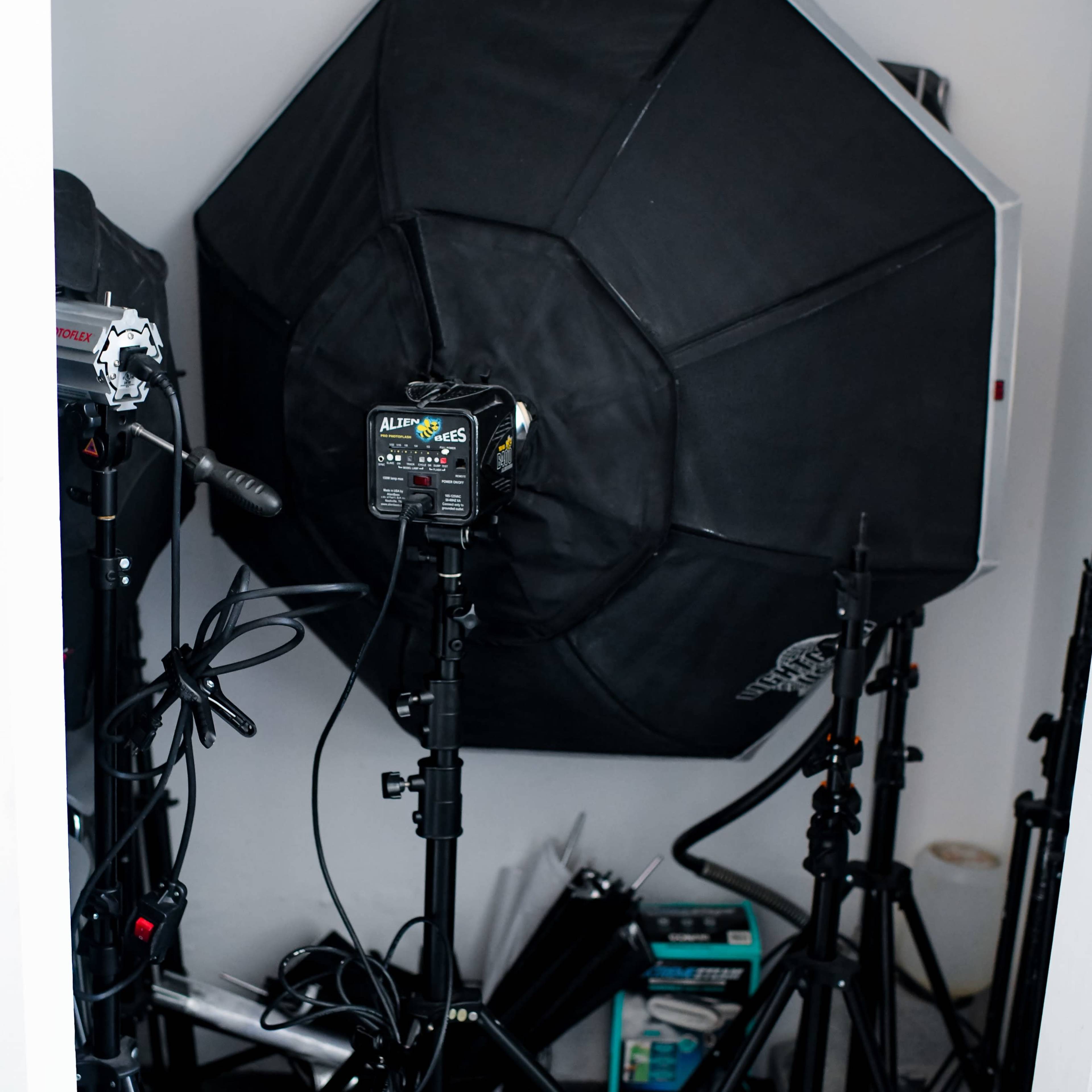 A black octagonal softbox and various lighting equipment set up in a storage area.
