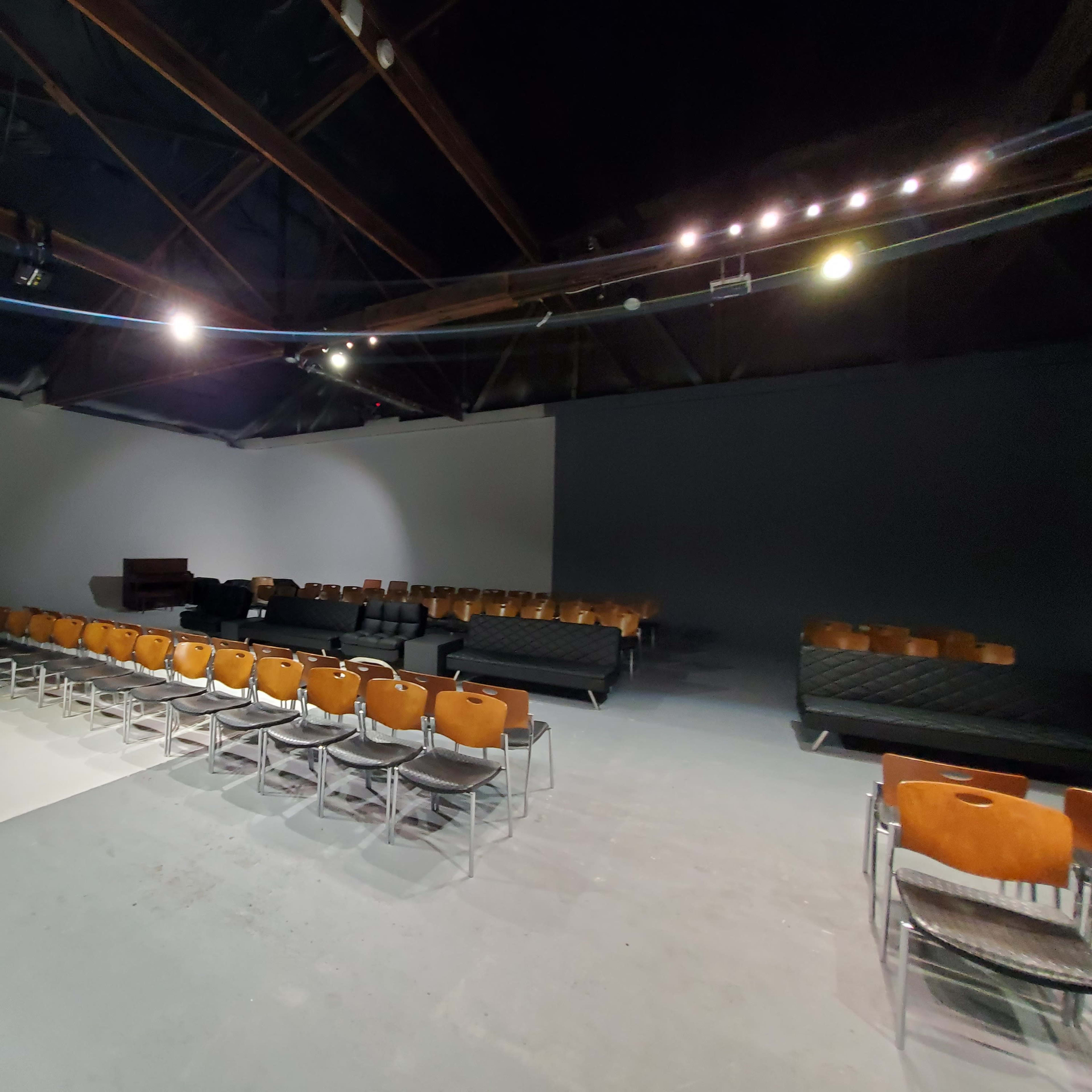 A spacious, empty room arranged with rows of chairs facing a projection screen on one wall.