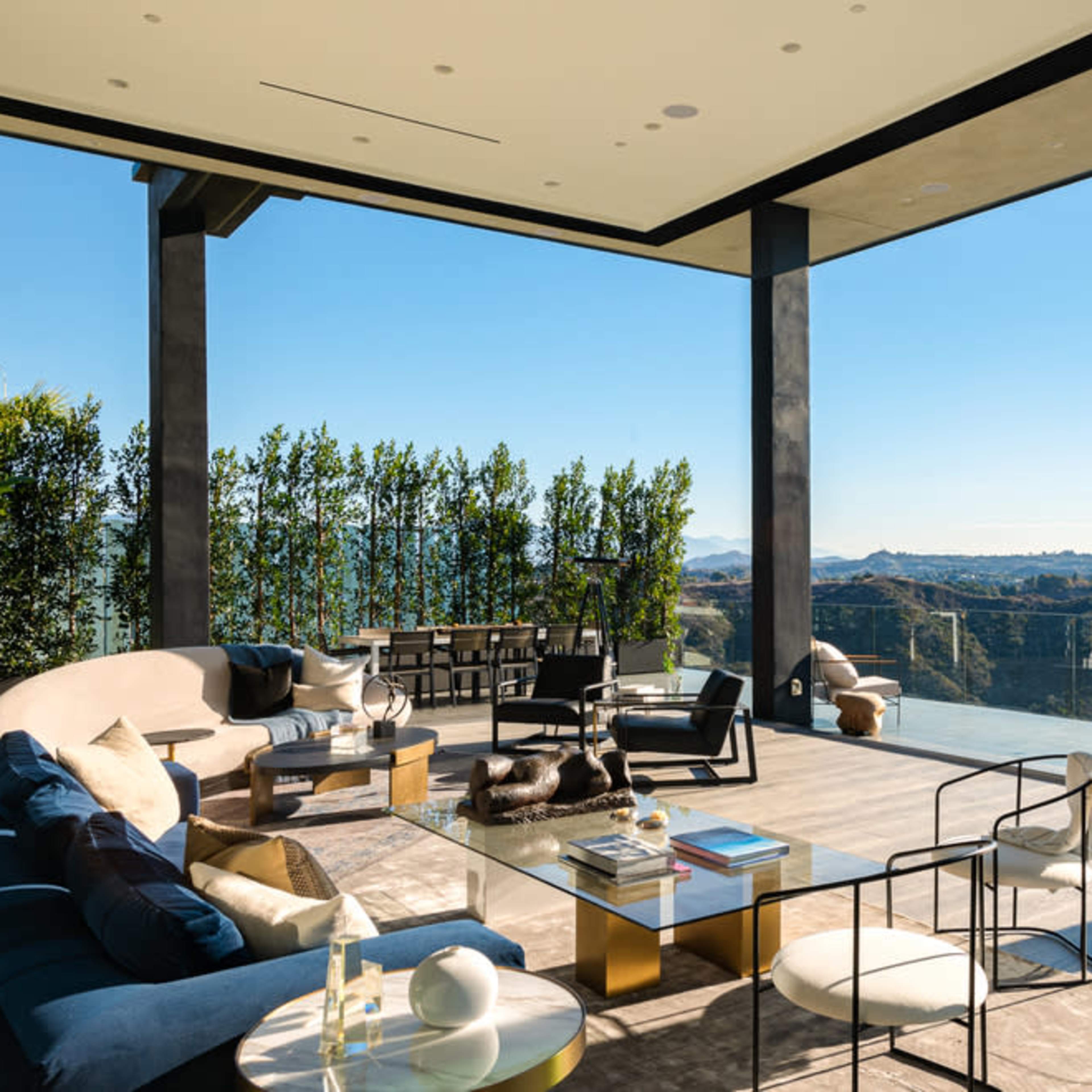 The spacious living room features large glass walls that offer a panoramic view of the surrounding hills and landscape.
