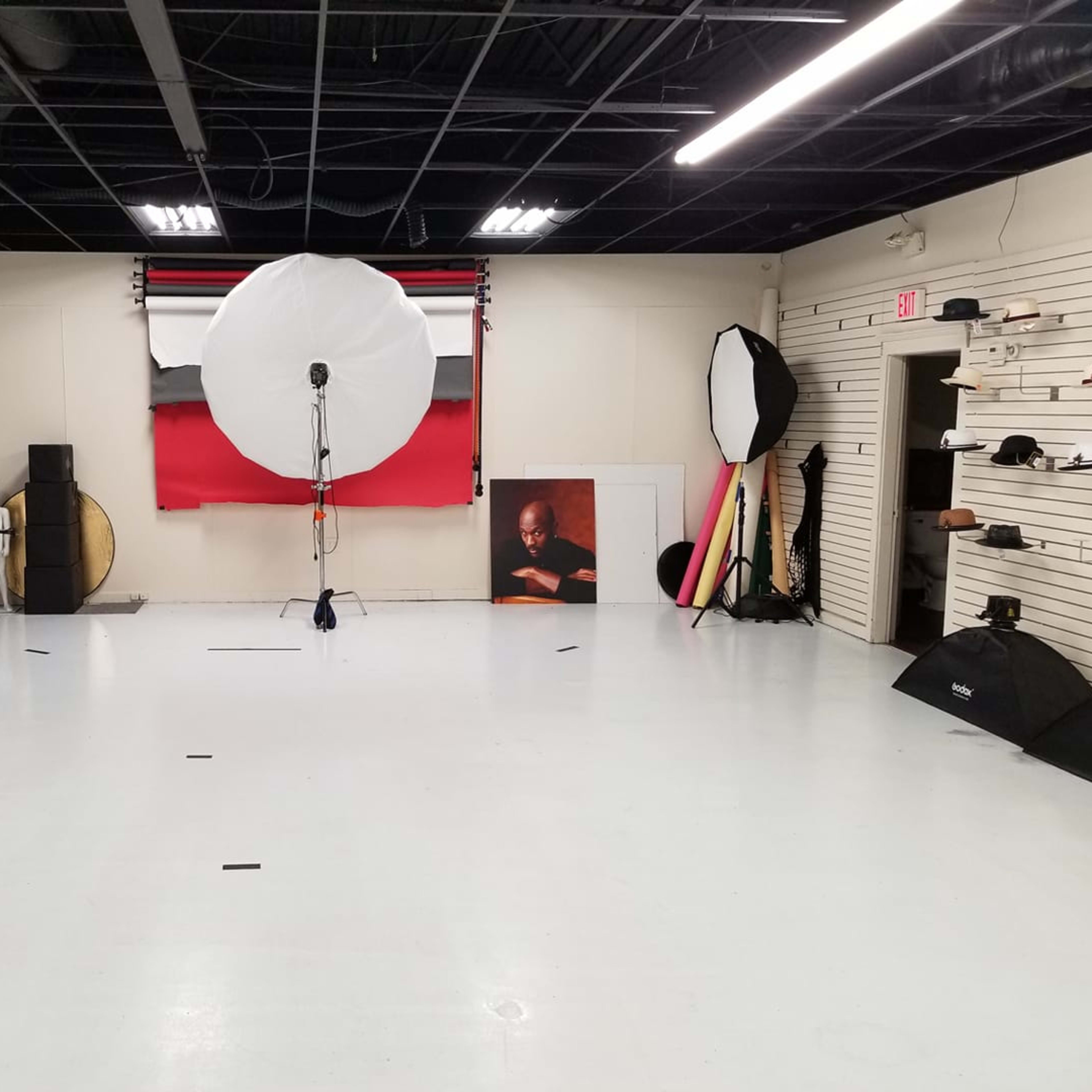 A photography studio with various lighting equipment, backdrops, and props arranged in a spacious, well-lit area.