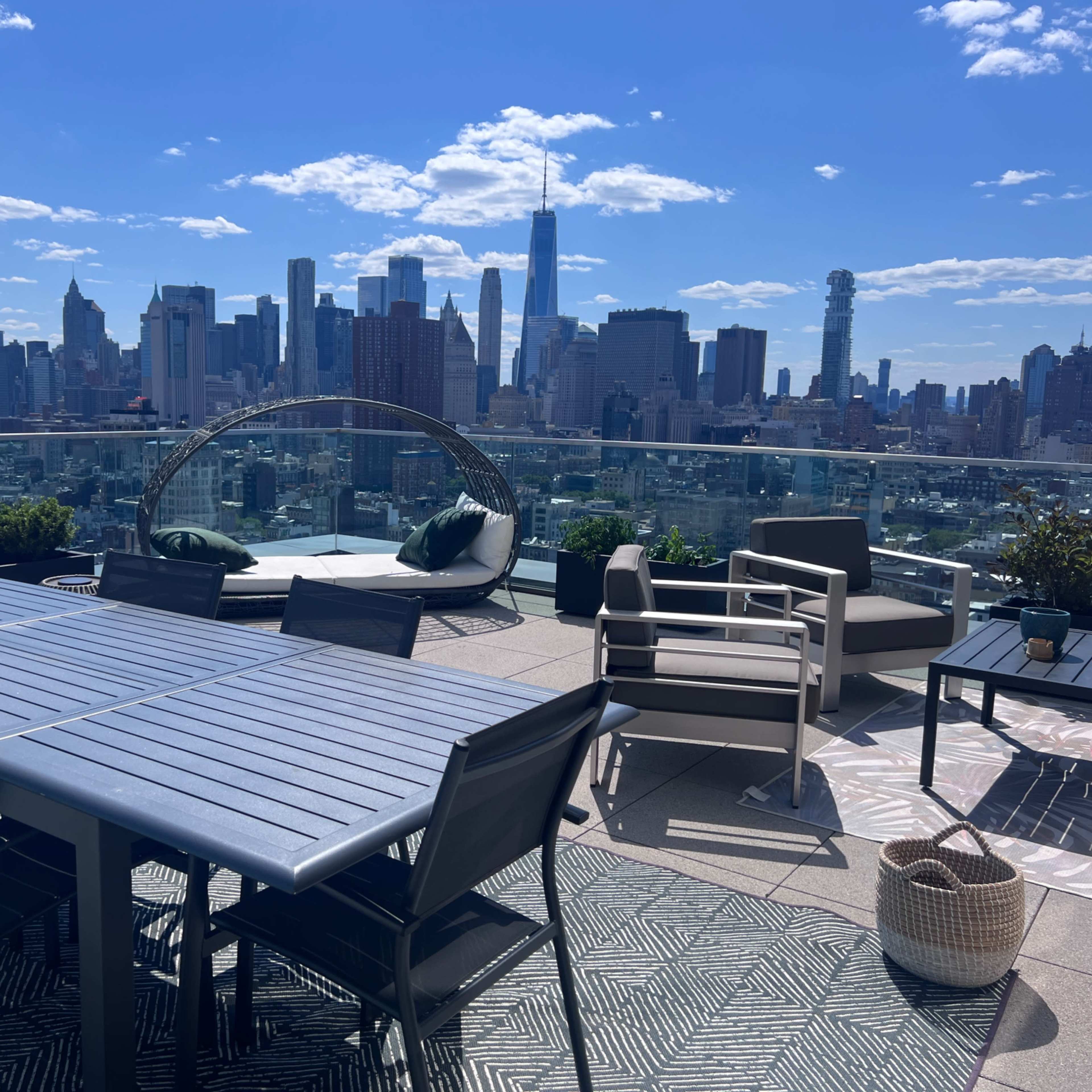 A rooftop terrace with outdoor furniture and a panoramic view of a city skyline.