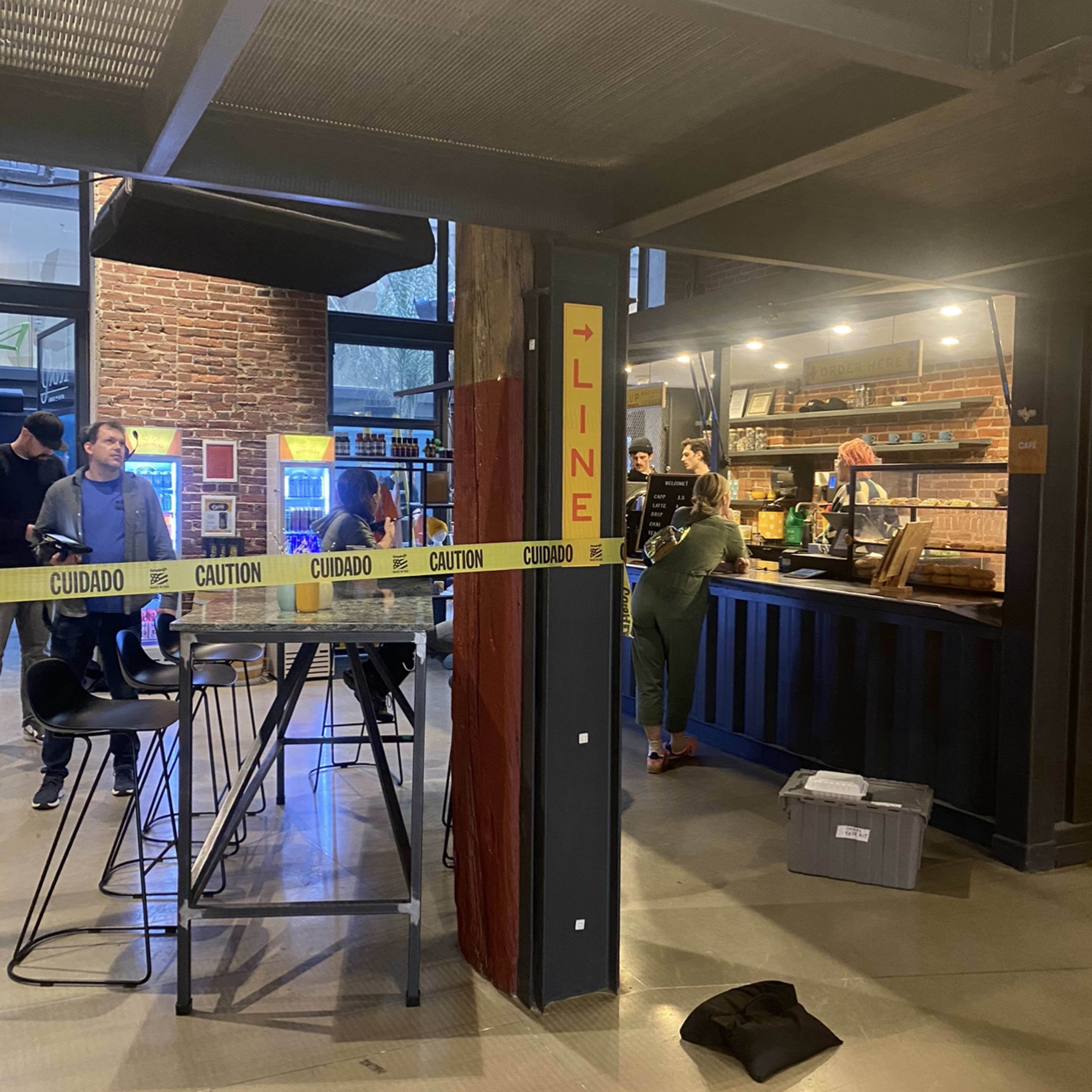 A bustling café scene features customers ordering at the counter, with a "LINE" sign and caution tape indicating the queue area.