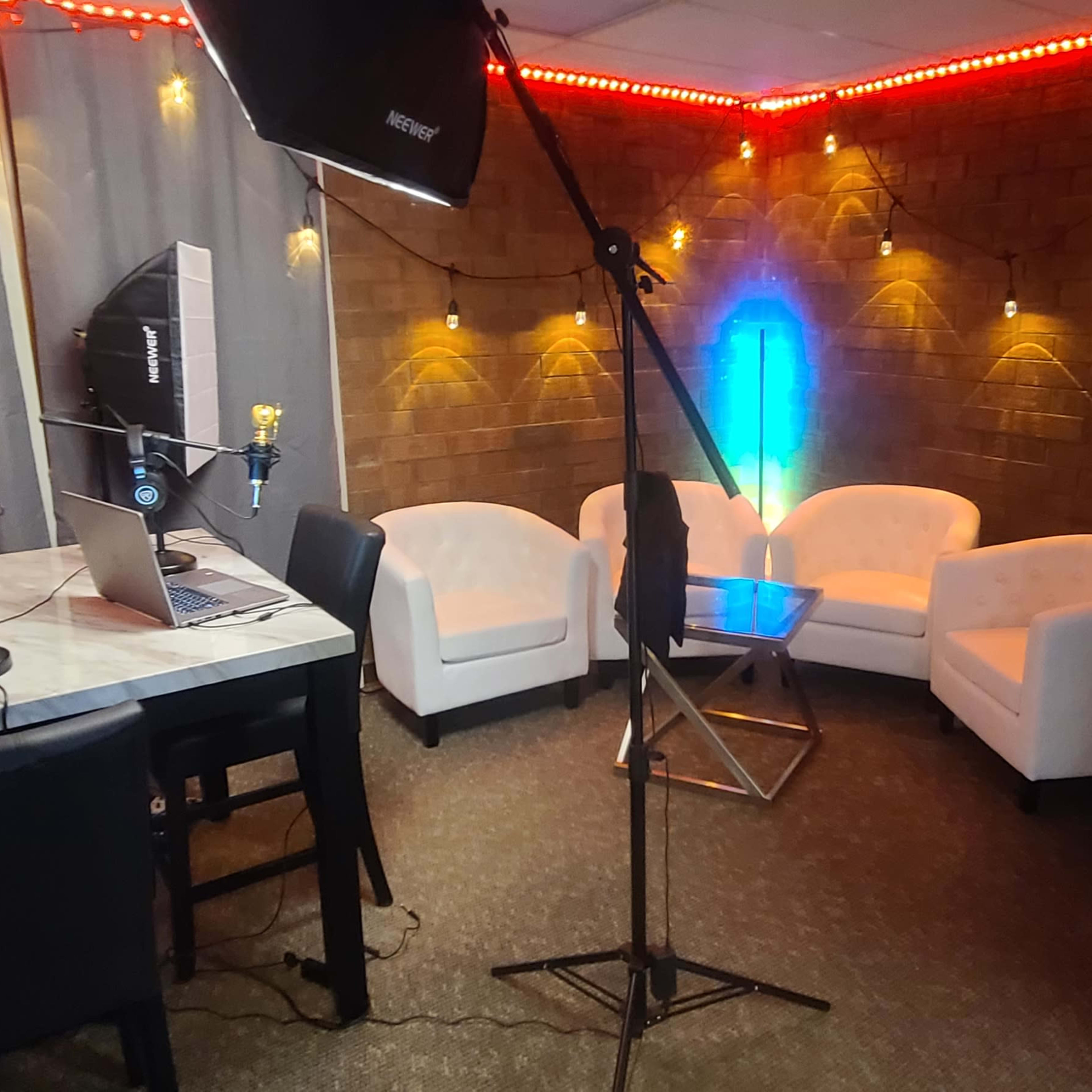 A recording studio with a table, chairs, microphones, and ambient lighting.