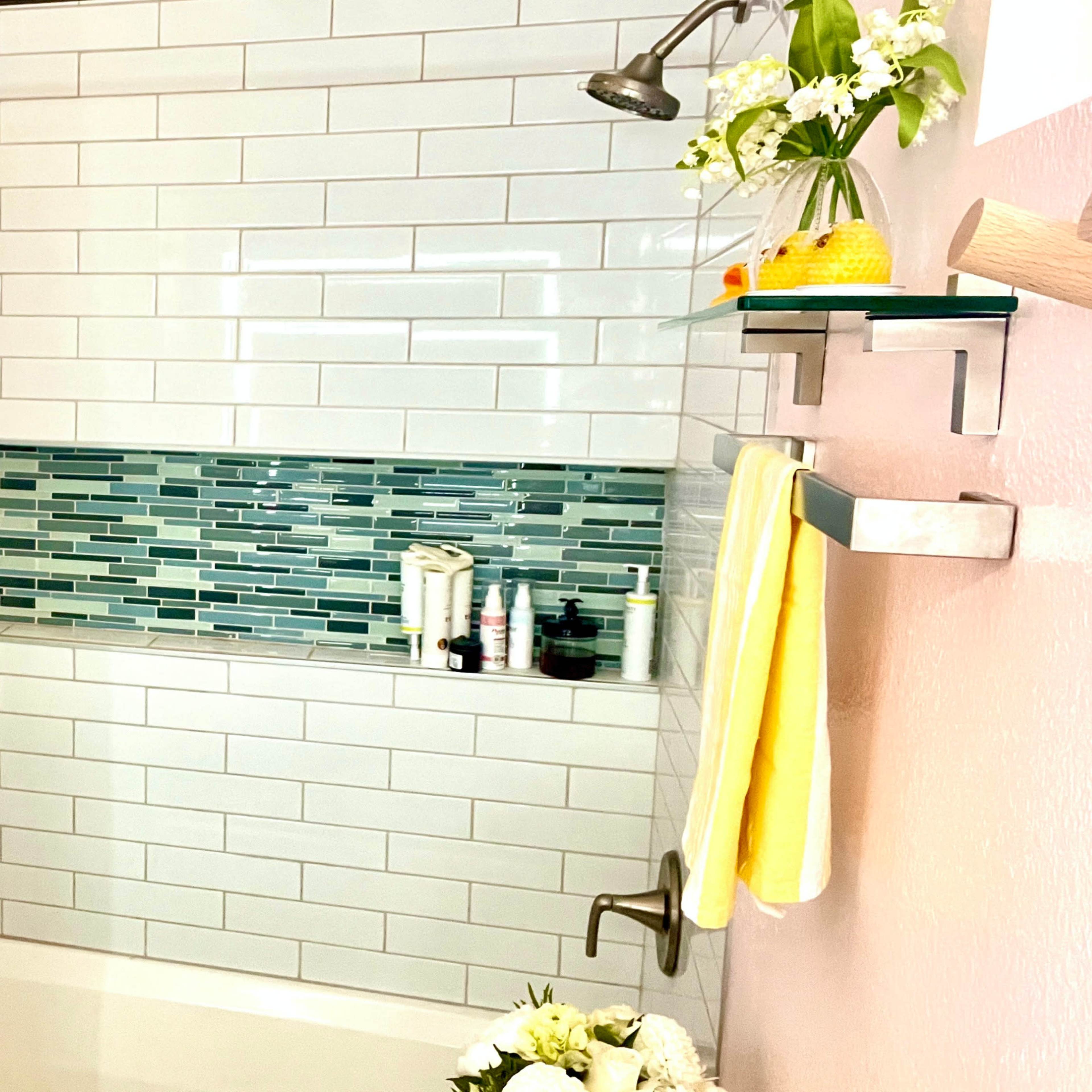 A bathroom with a bathtub, a shower curtain featuring an ombre pattern, and shelves displaying various bathroom products.