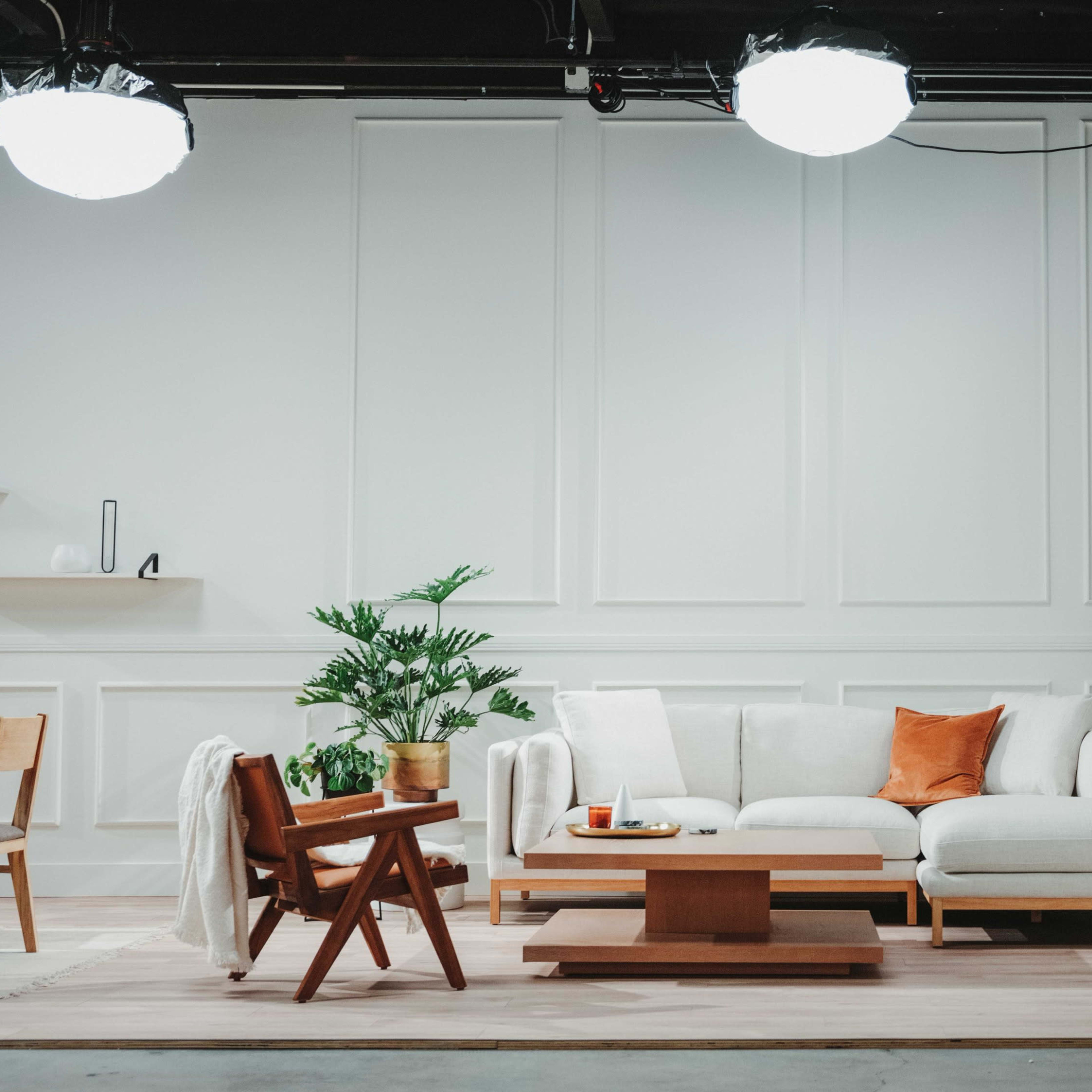 A modern living room setup with a white couch, wooden coffee table, and a dining area featuring a wooden table and chairs.