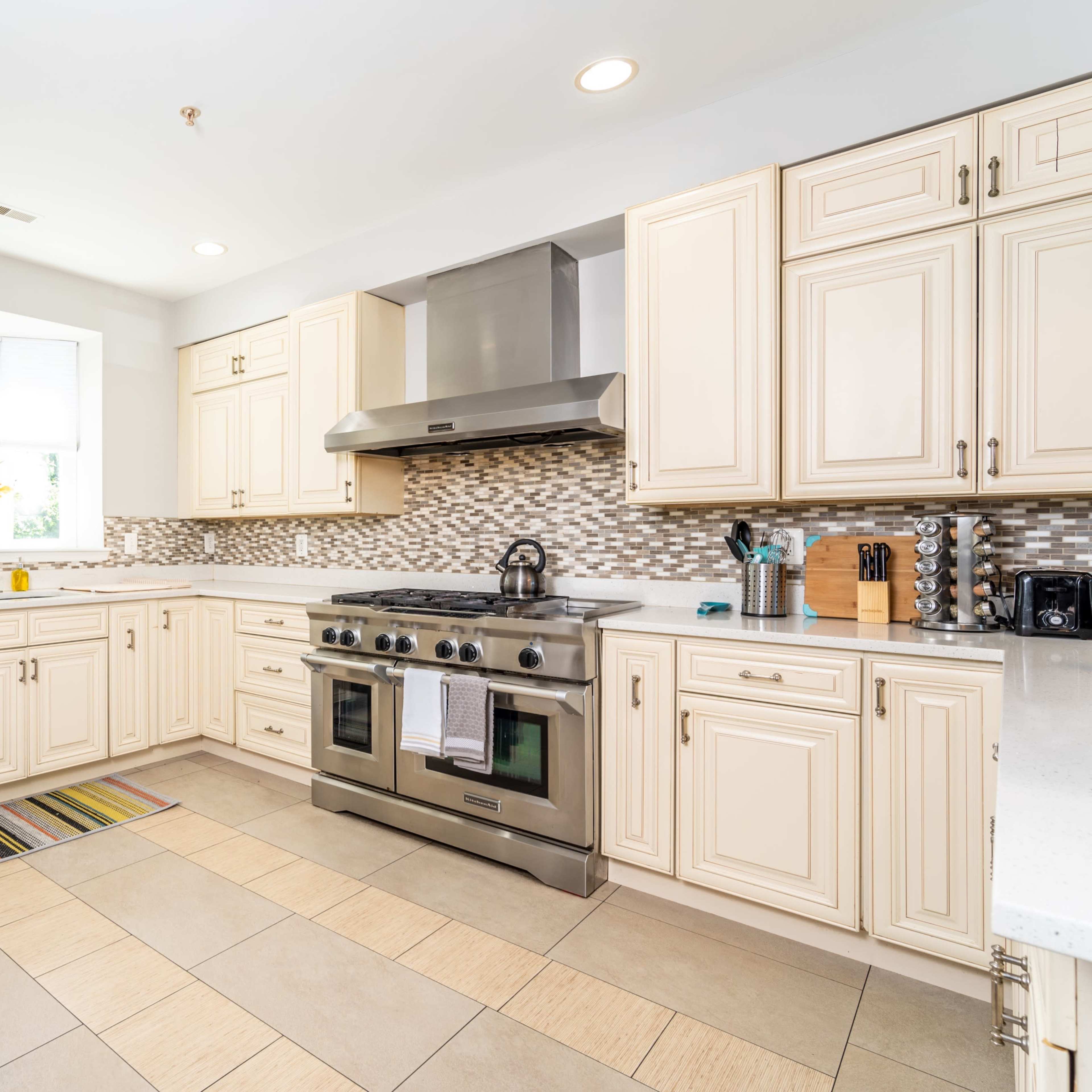 The kitchen features cream-colored cabinets, stainless steel appliances, and a tiled floor.