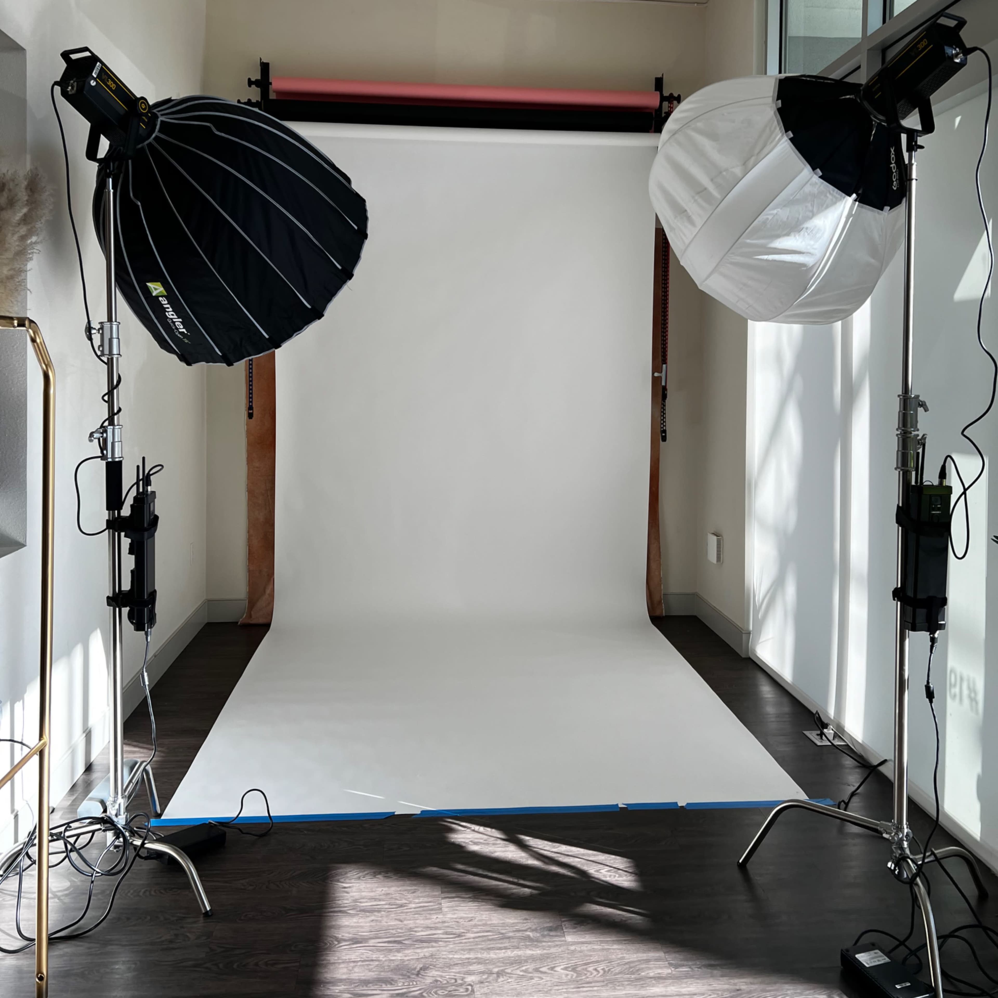 A photography studio setup featuring two large softbox lights positioned on either side of a blank white backdrop.