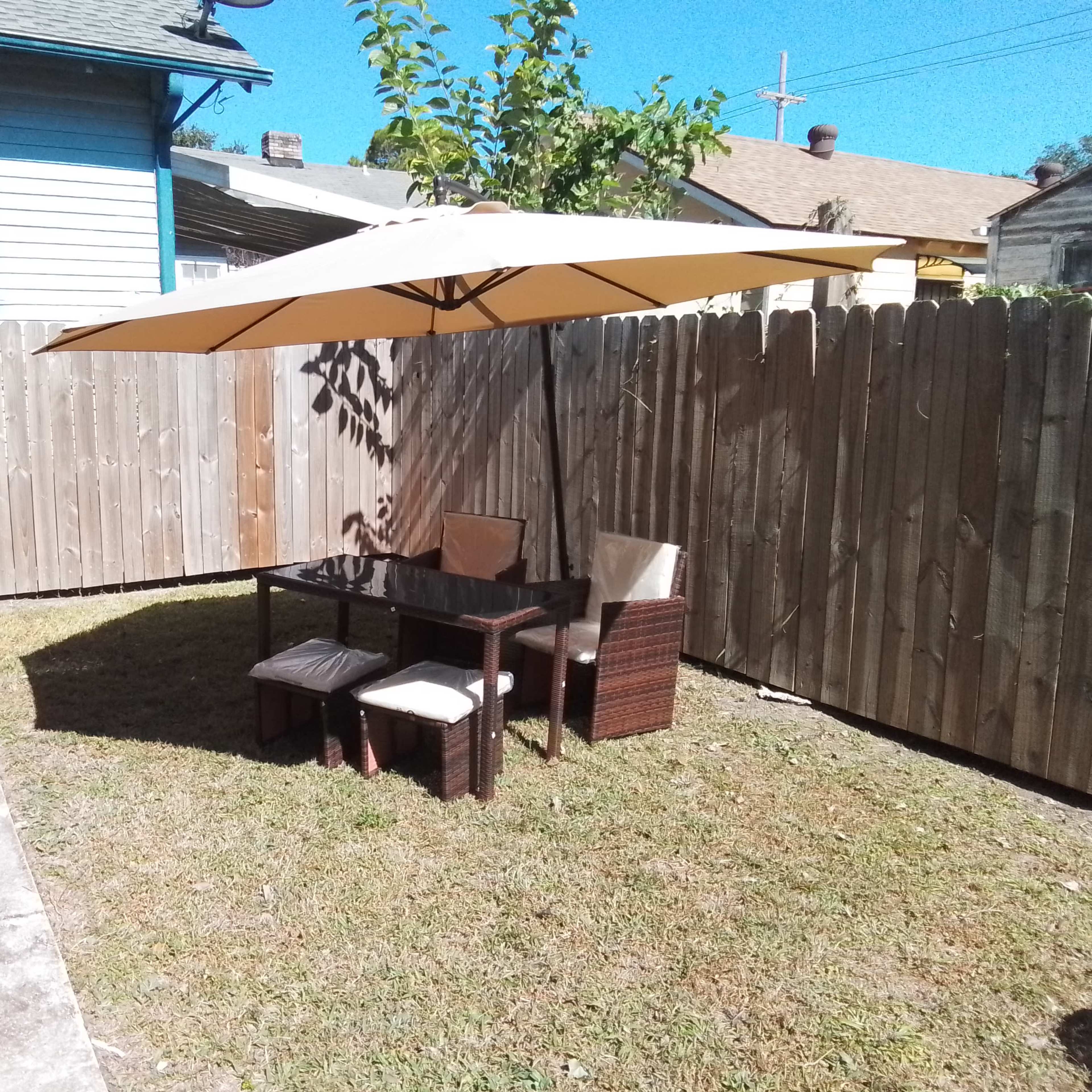 A small outdoor patio area features a table with two chairs under a large umbrella, enclosed by a wooden fence.