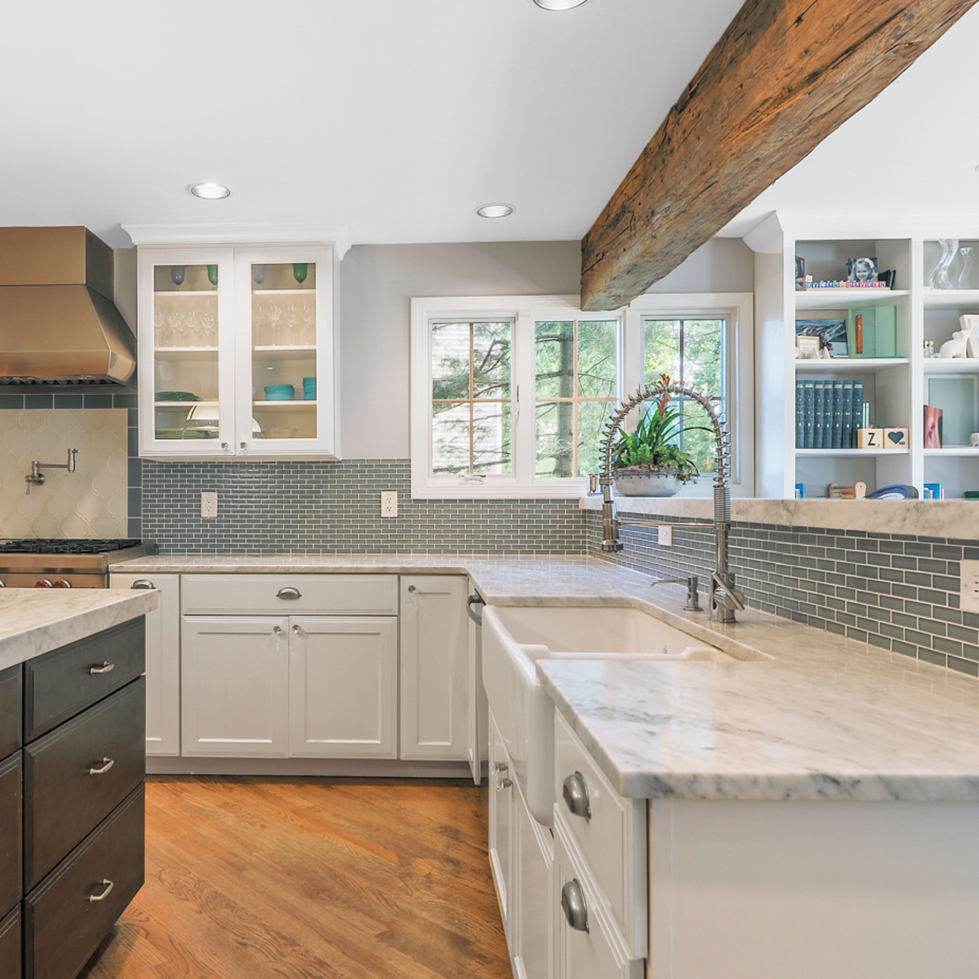 The kitchen features a large central island with a marble countertop, white cabinetry, and a tile backsplash.