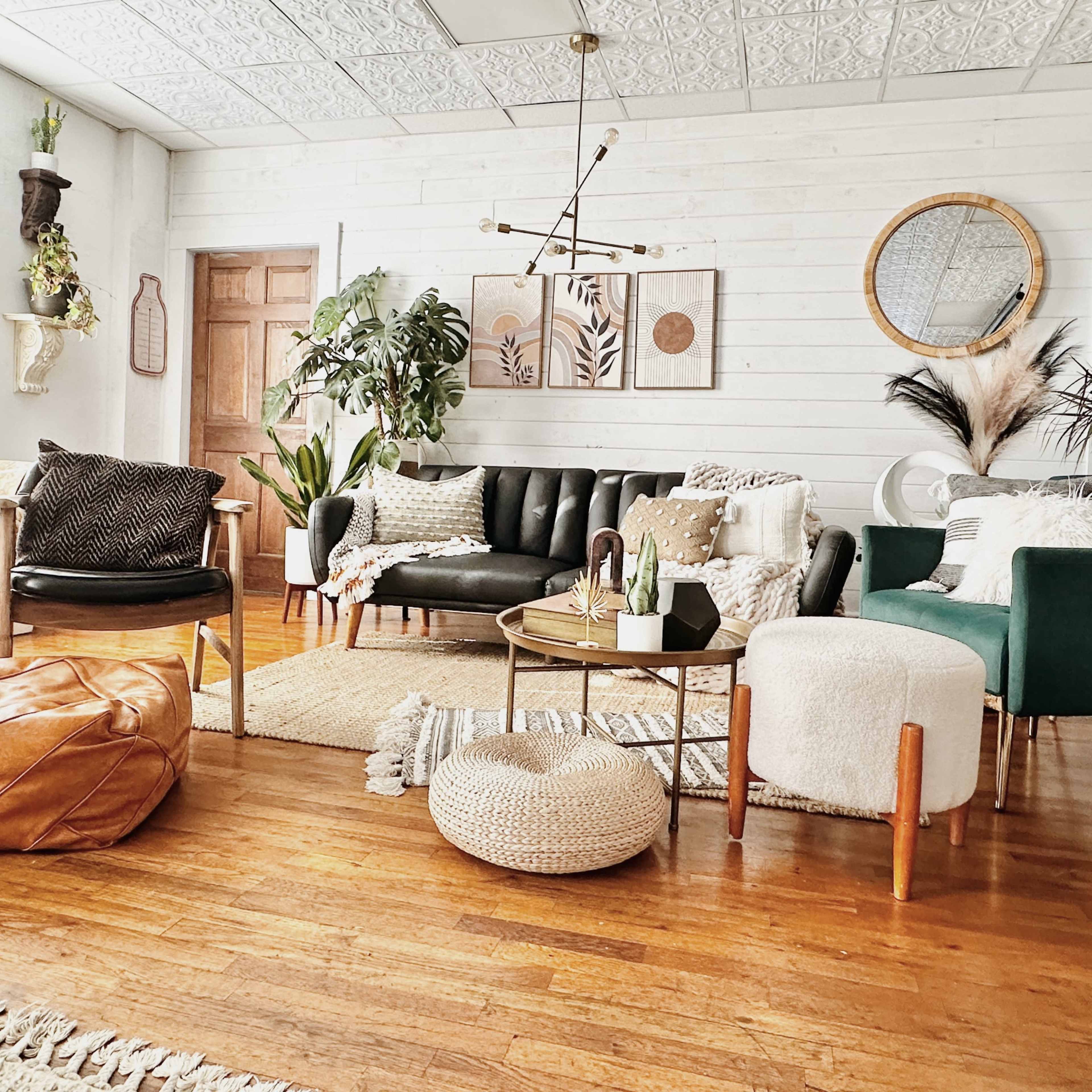 A stylish living room featuring a variety of seating options, decorative plants, and a round coffee table on a wooden floor.