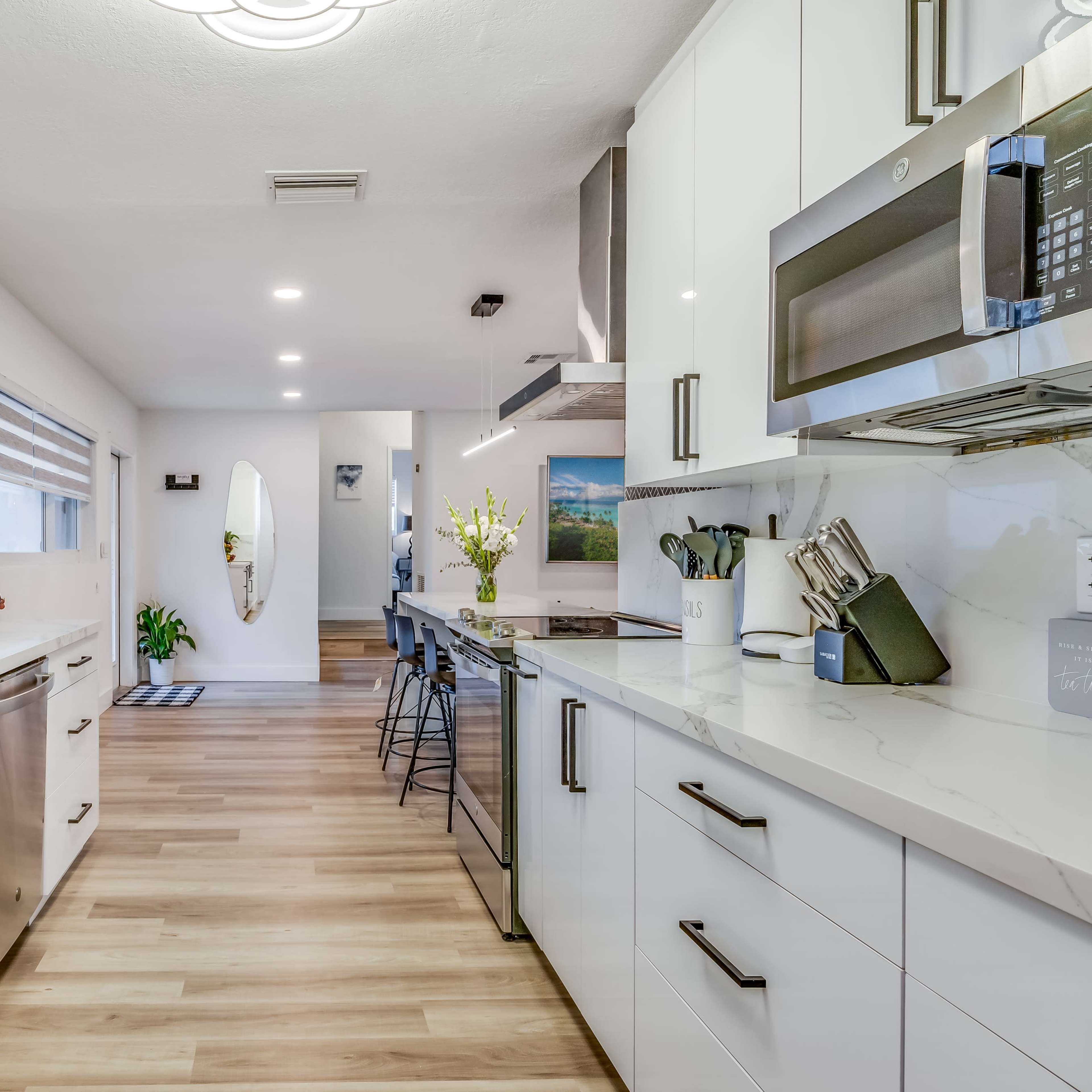A modern kitchen with white cabinetry, stainless steel appliances, and a window that allows natural light.