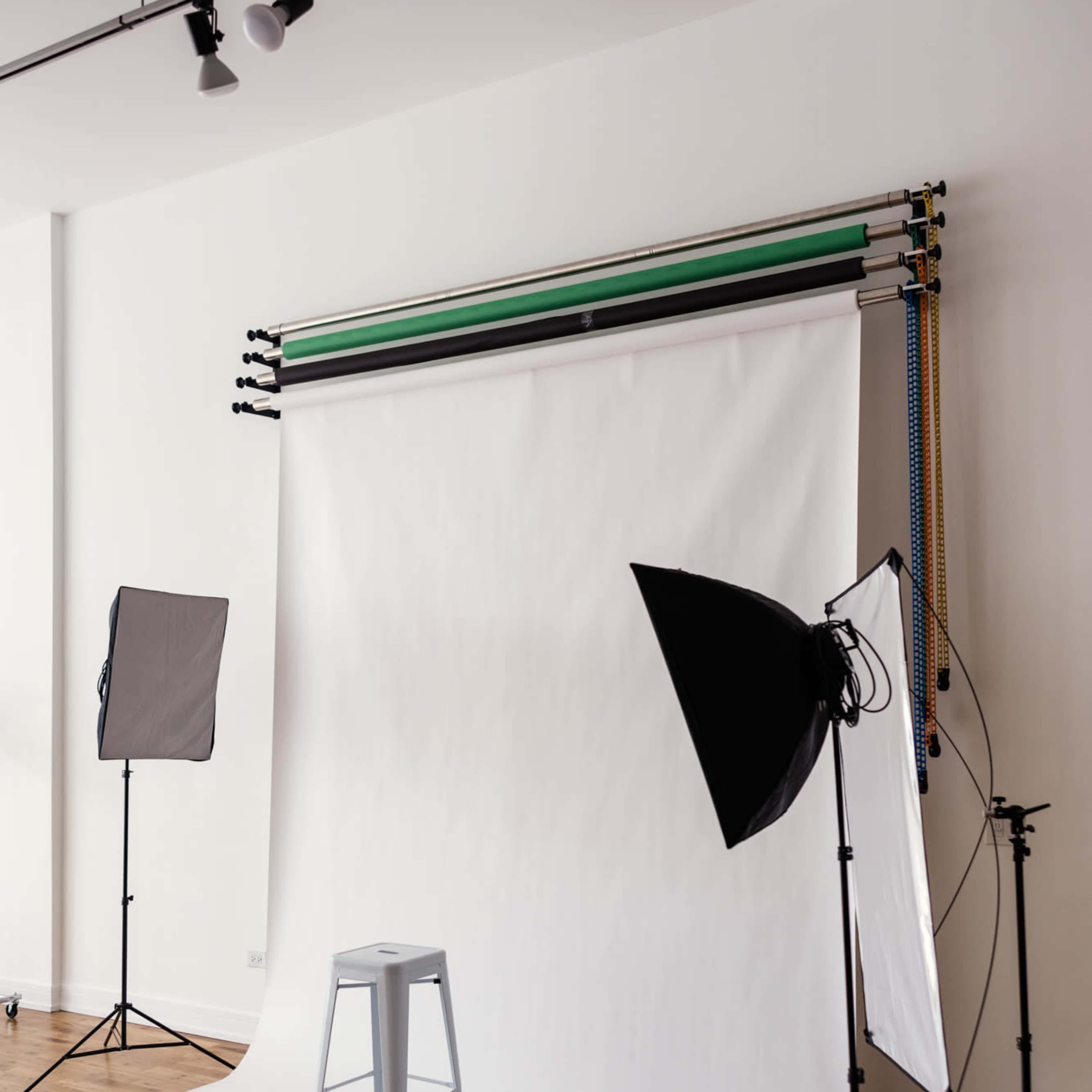 A photography setup featuring a white backdrop, a stool, and multiple studio lights arranged around the scene.