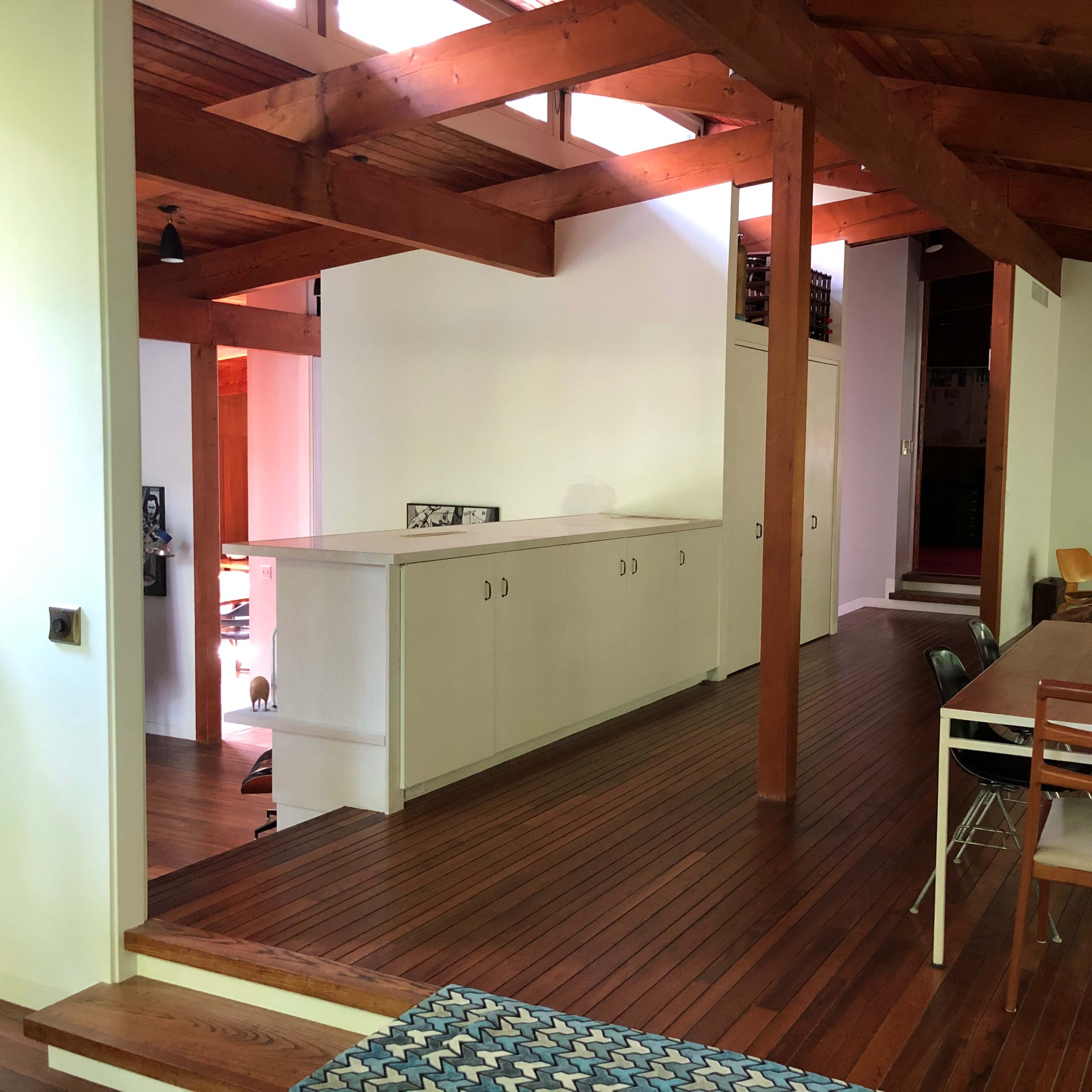 A modern interior of a home with wooden beams, a dining table, and a kitchen area in the background.