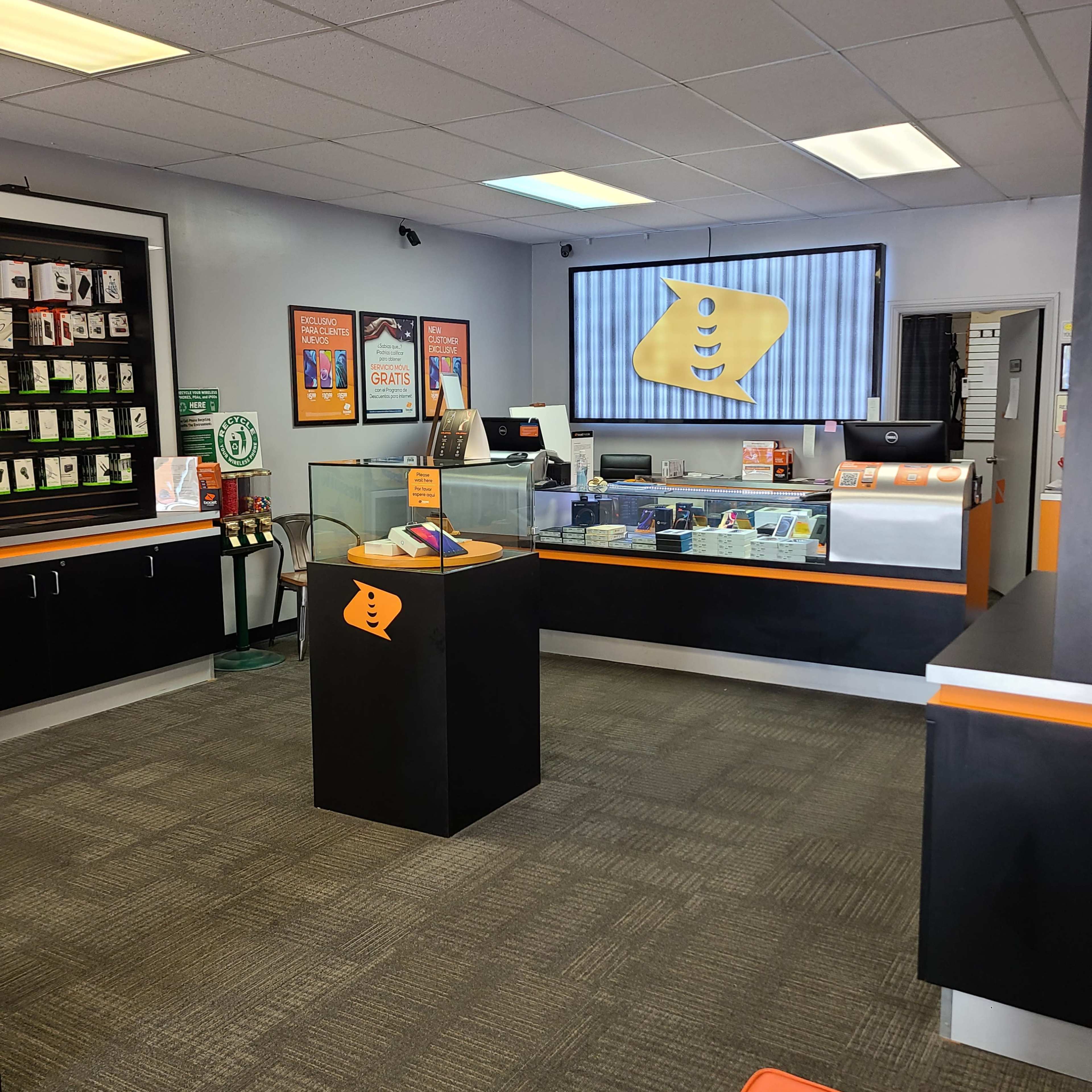 The interior of a retail store featuring a product display area with a counter, a wall of merchandise, and a large screen displaying the store's logo.