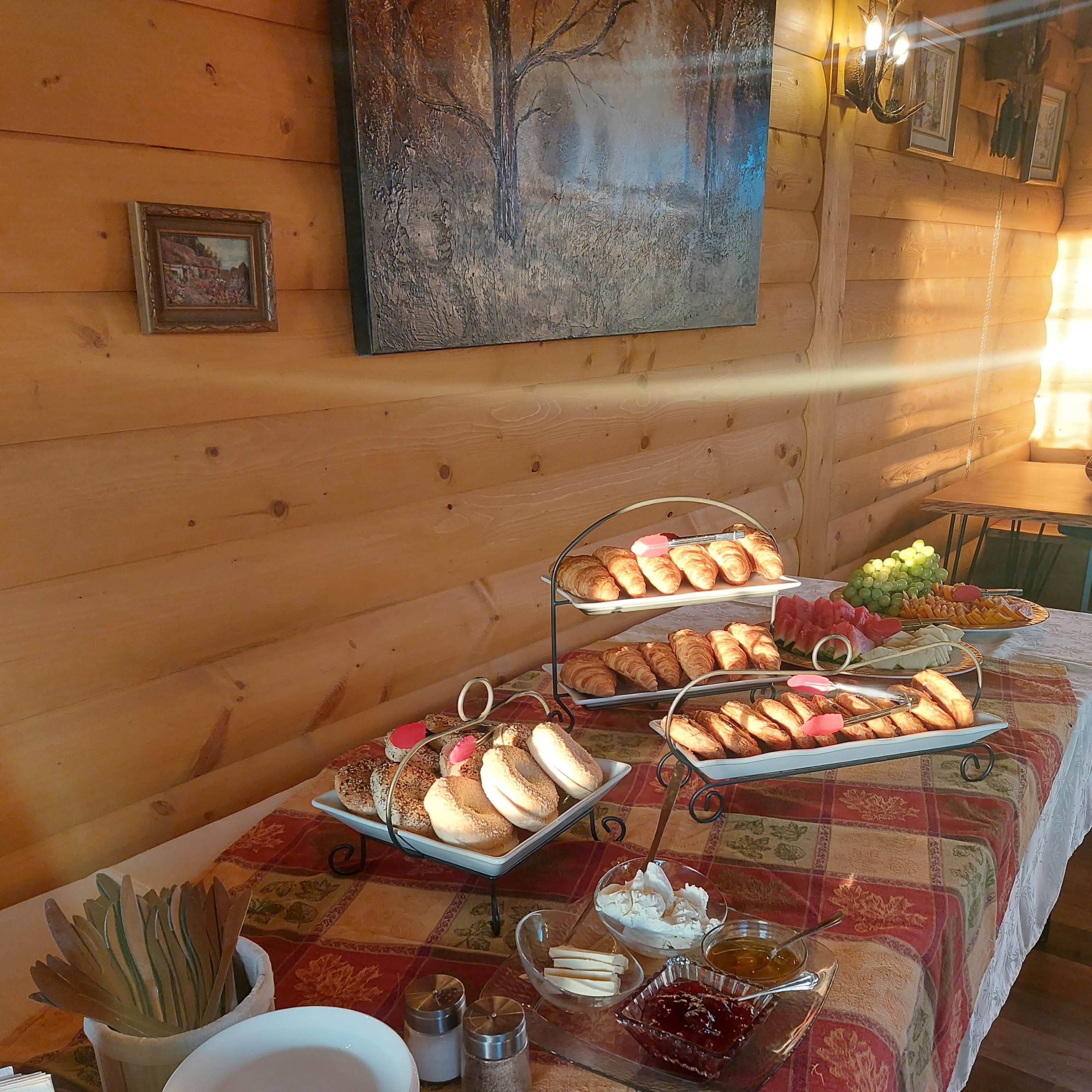 A table is set with a variety of baked goods, including pastries and bread, alongside plates, utensils, and condiments.