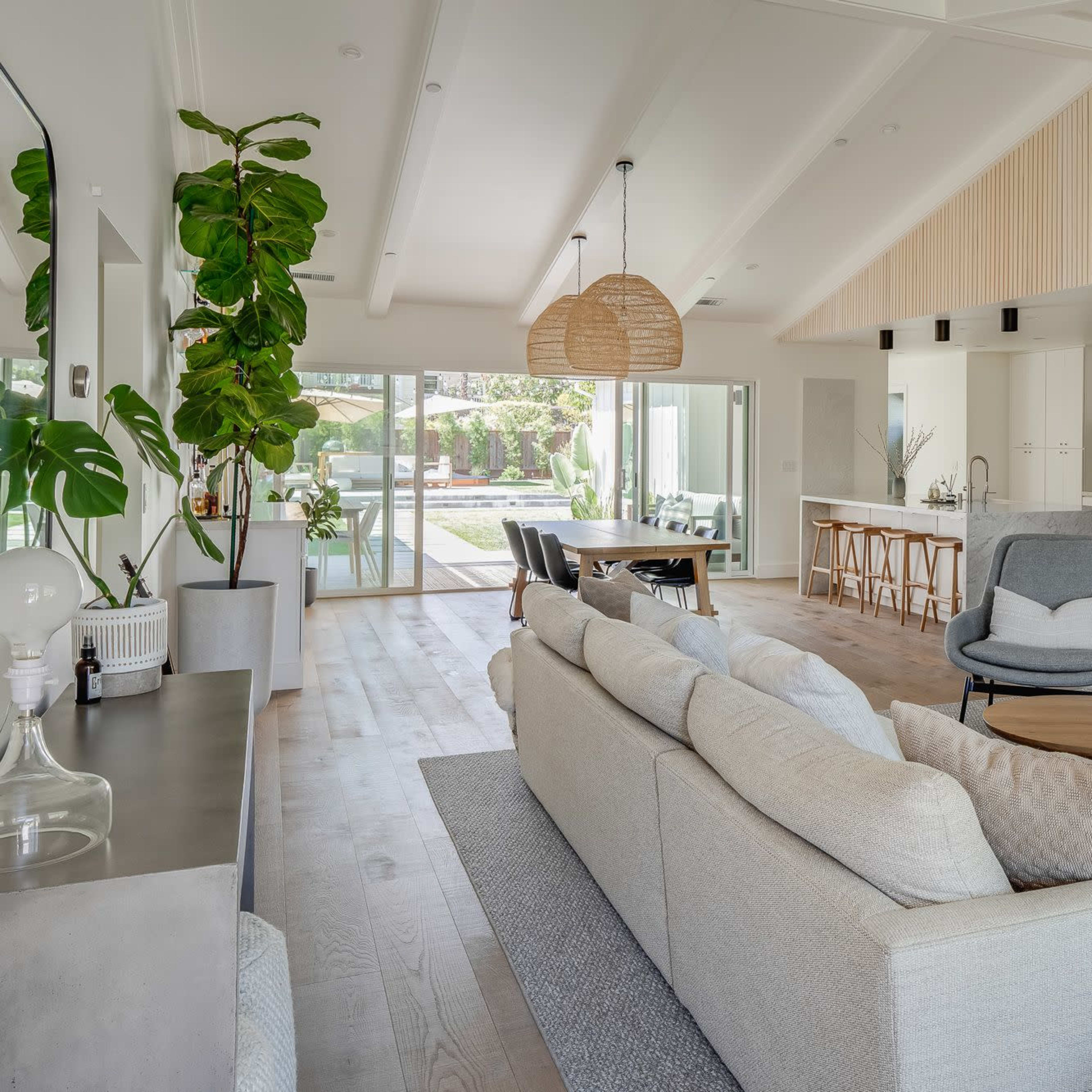 A modern living room featuring a light-colored sectional sofa, a wooden coffee table, and large windows overlooking a patio area.