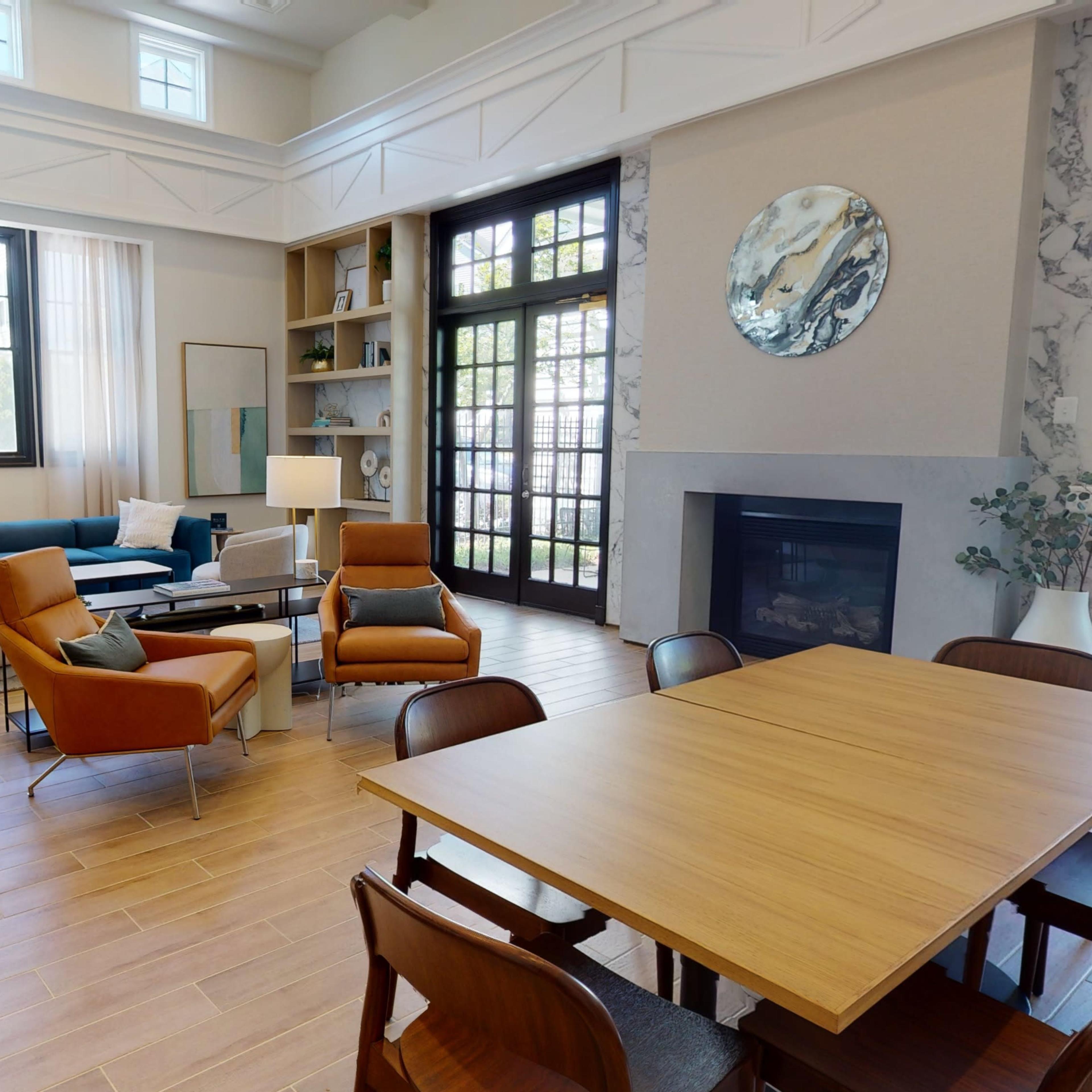 A modern living space featuring a sofa, armchairs, a coffee table, a dining table with chairs, and a large window allowing natural light to enter.