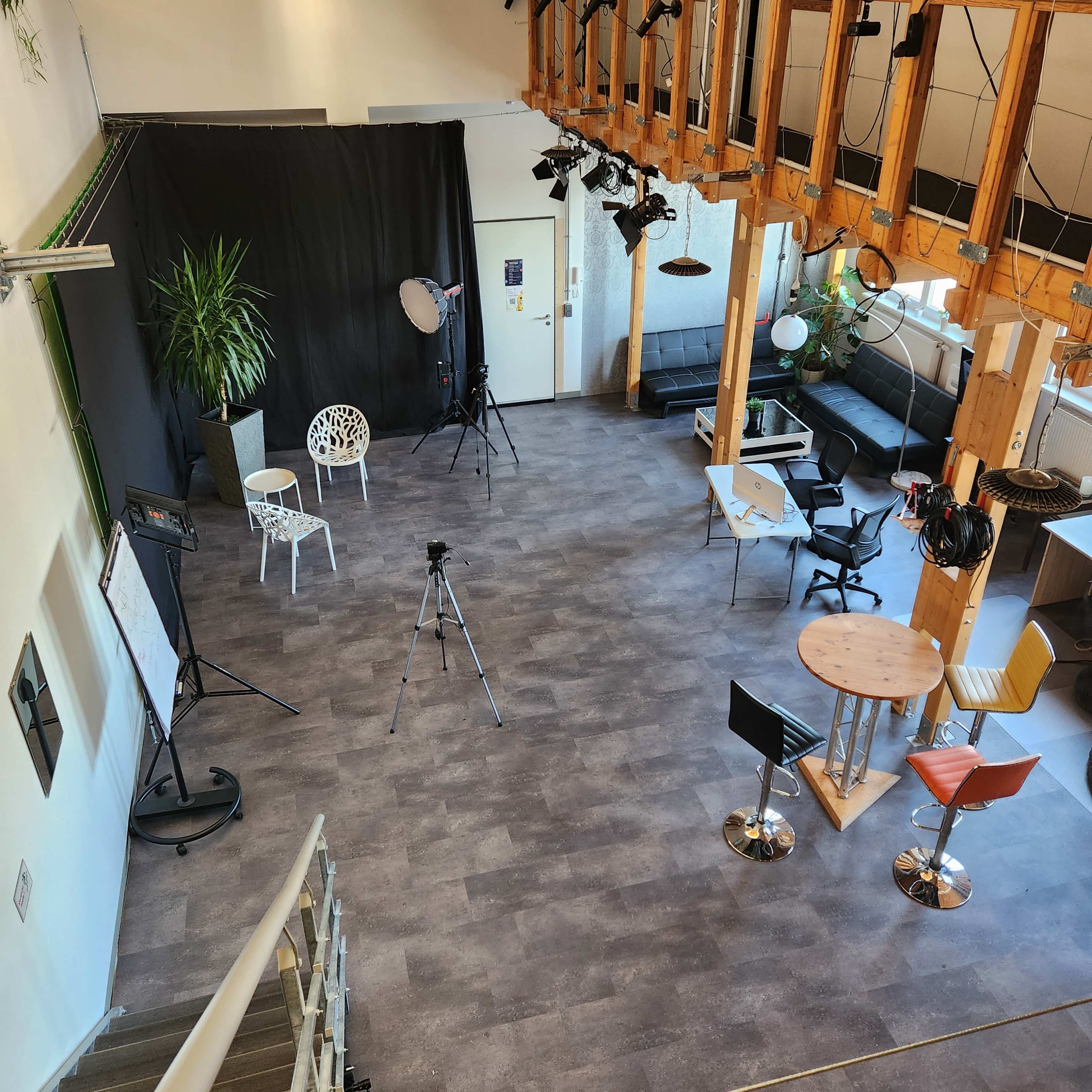 A spacious room with a black backdrop, various seating arrangements, and photography equipment set up for a shoot.