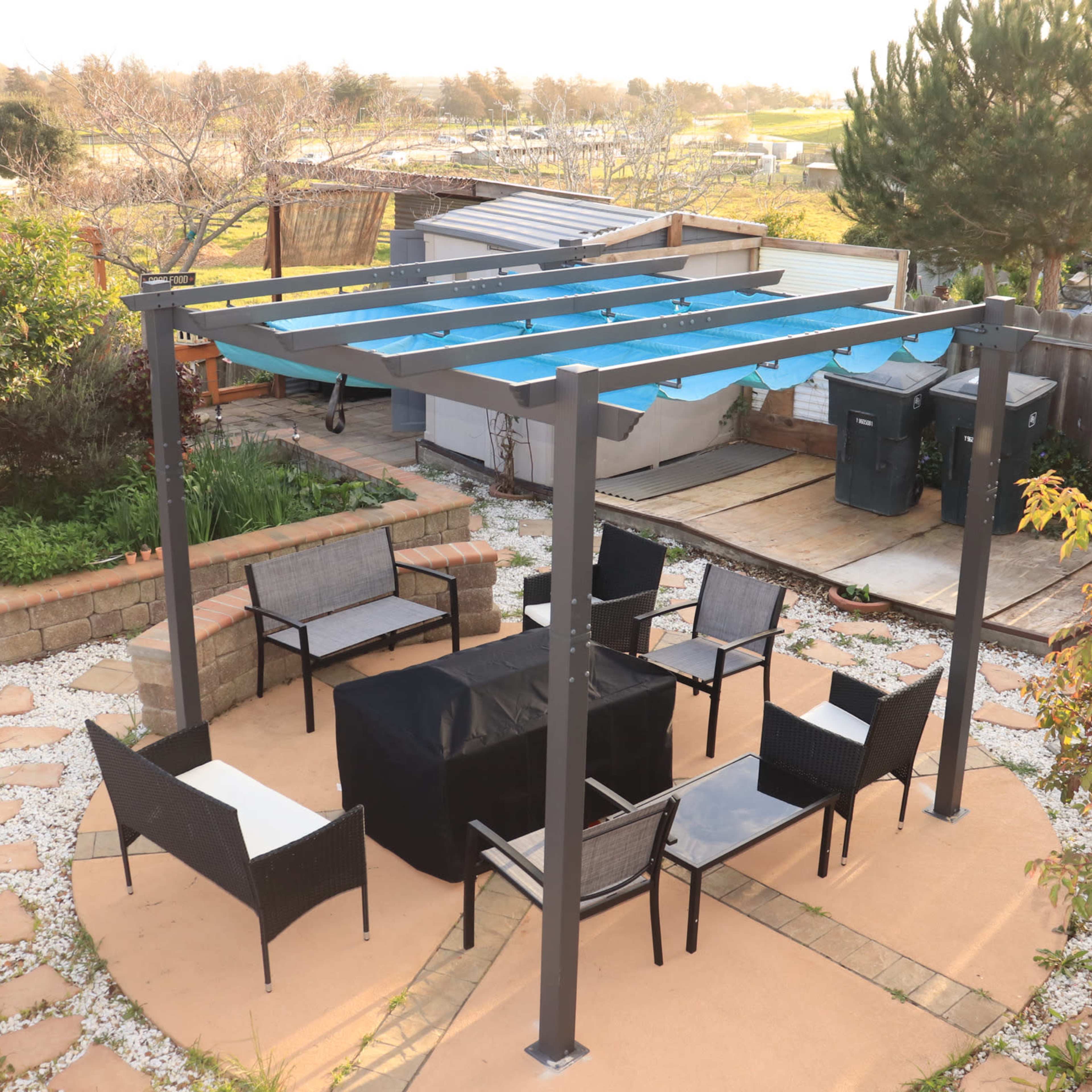 A patio area with a metal pergola, outdoor seating, and a square table in a landscaped yard.