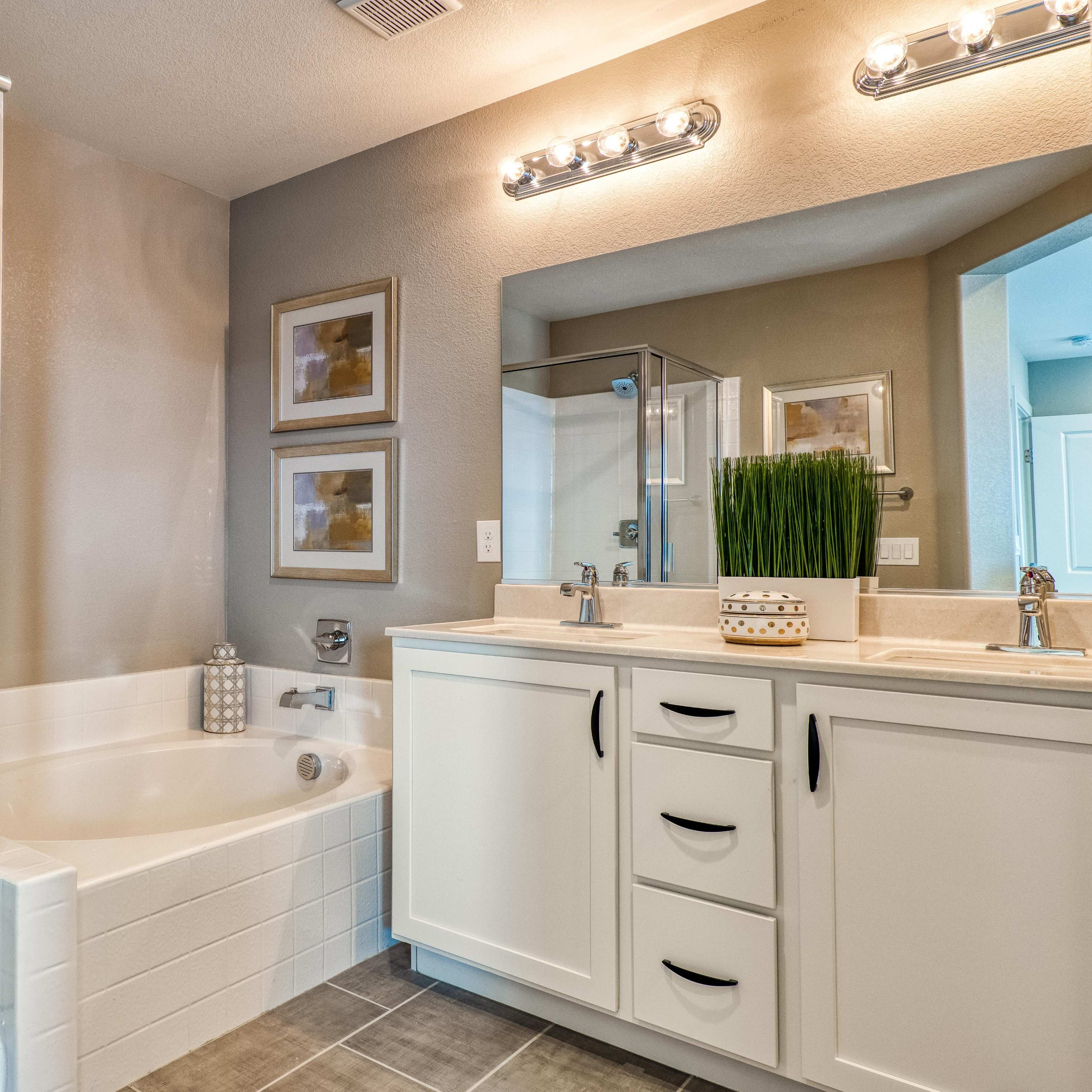 A modern bathroom featuring a glass-enclosed shower, a freestanding bathtub, and a double vanity with white cabinetry.
