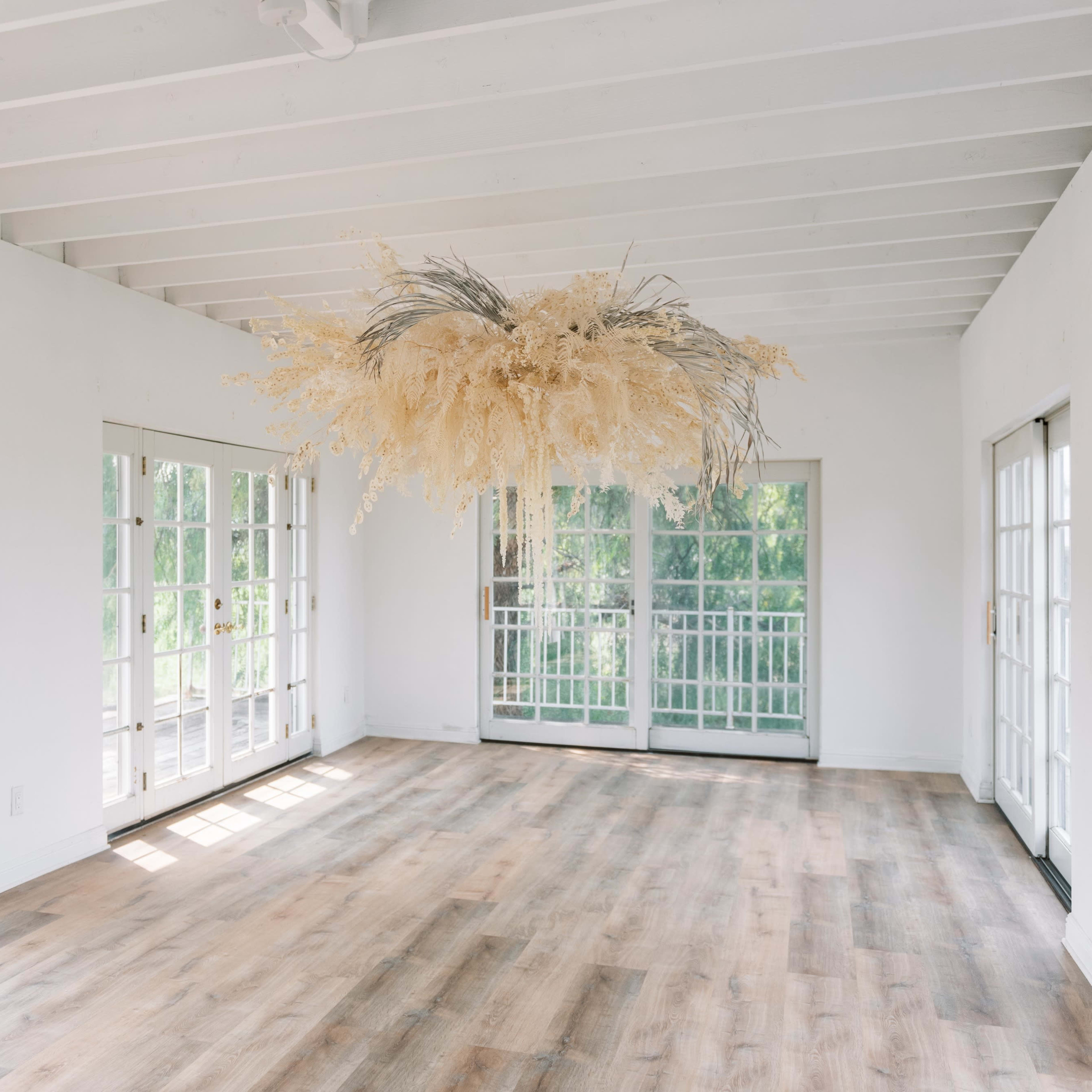 The room features large windows on two sides and a prominent floral arrangement suspended from the ceiling.
