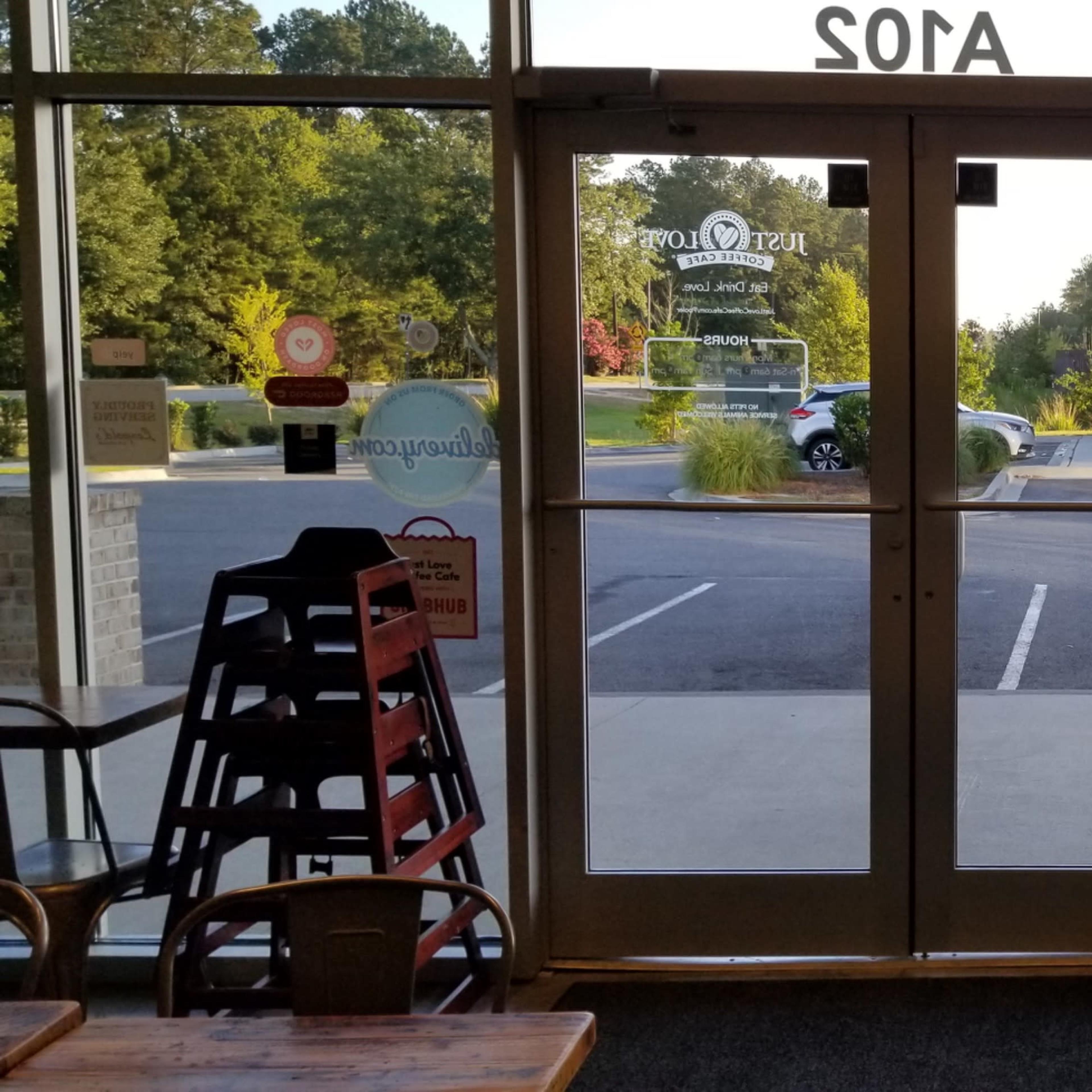 The interior of a café with a view of an empty parking lot through large glass doors.
