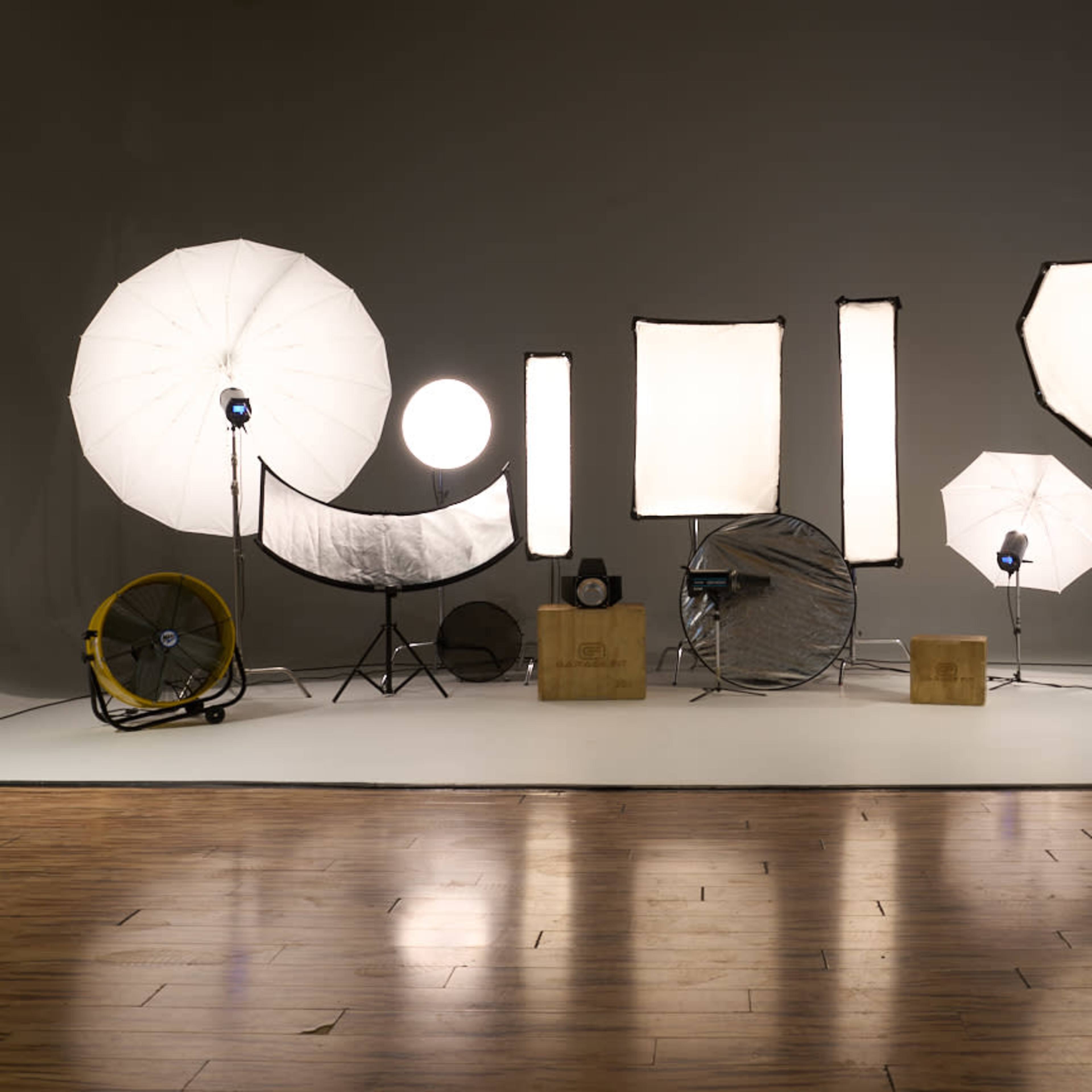 A photography setup with various light modifiers and equipment arranged on a white backdrop.