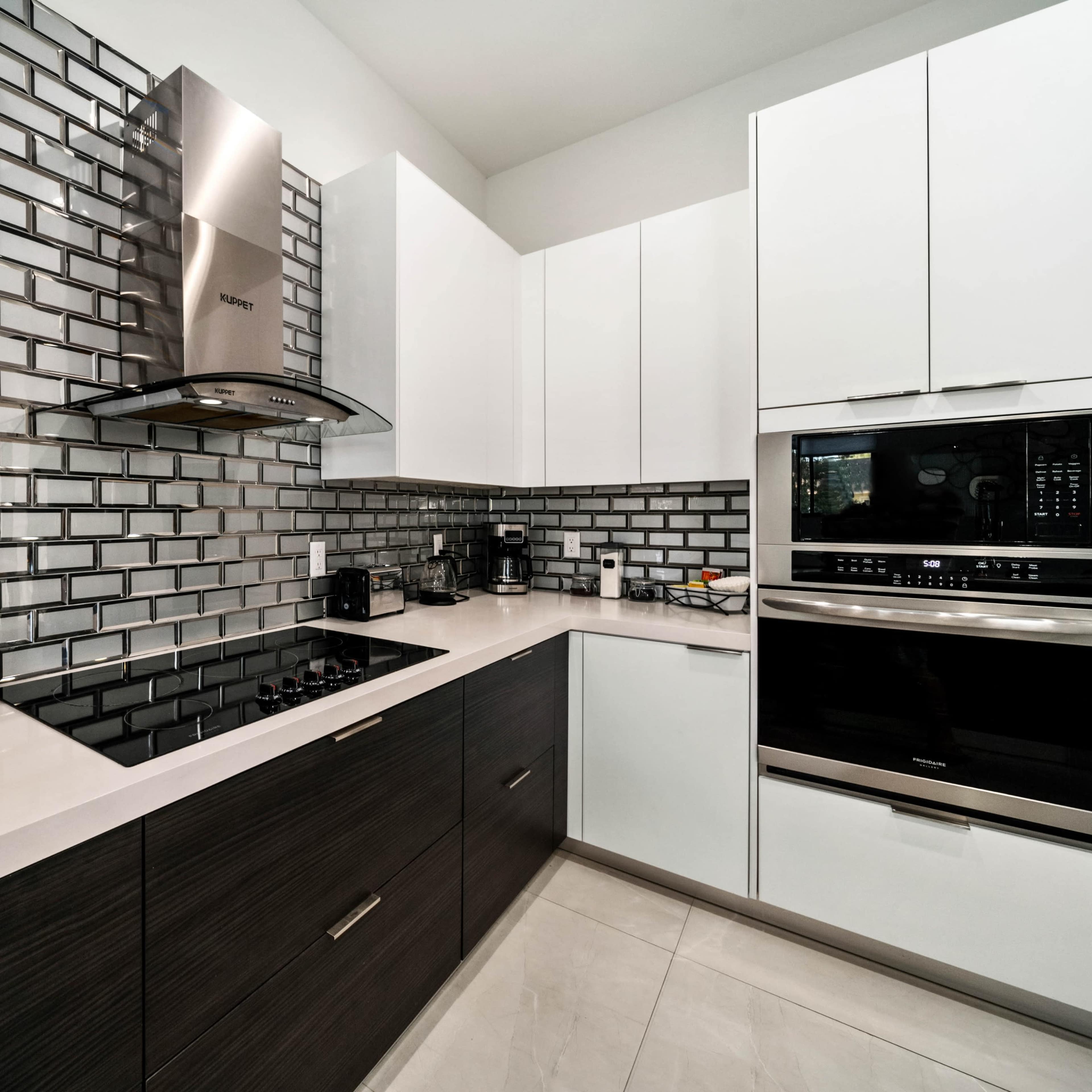 A modern kitchen features a gray tiled backsplash, stainless steel appliances, and sleek cabinetry.