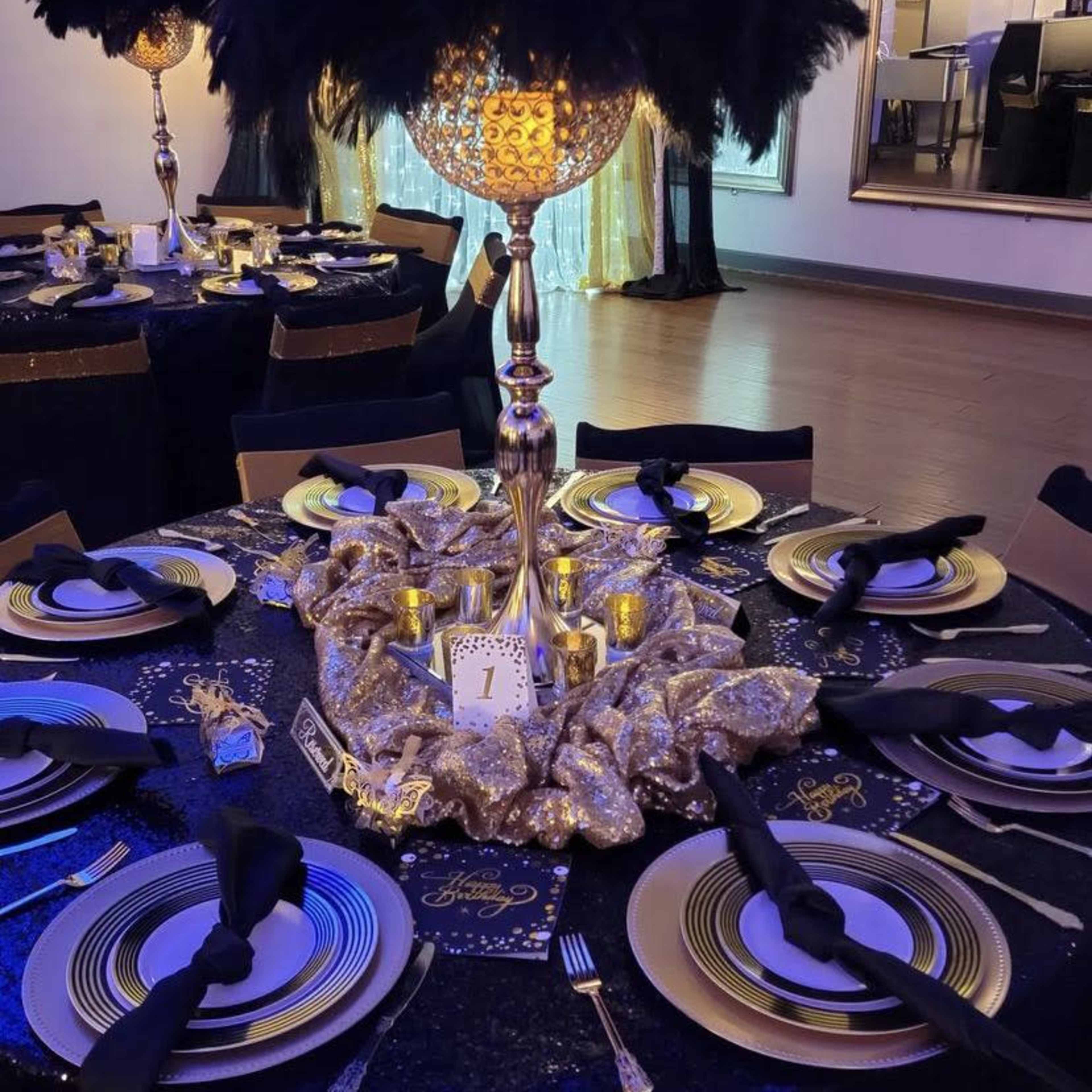 A lavishly decorated dining table set with black and gold tableware, shimmering centerpieces, and ornate place settings.